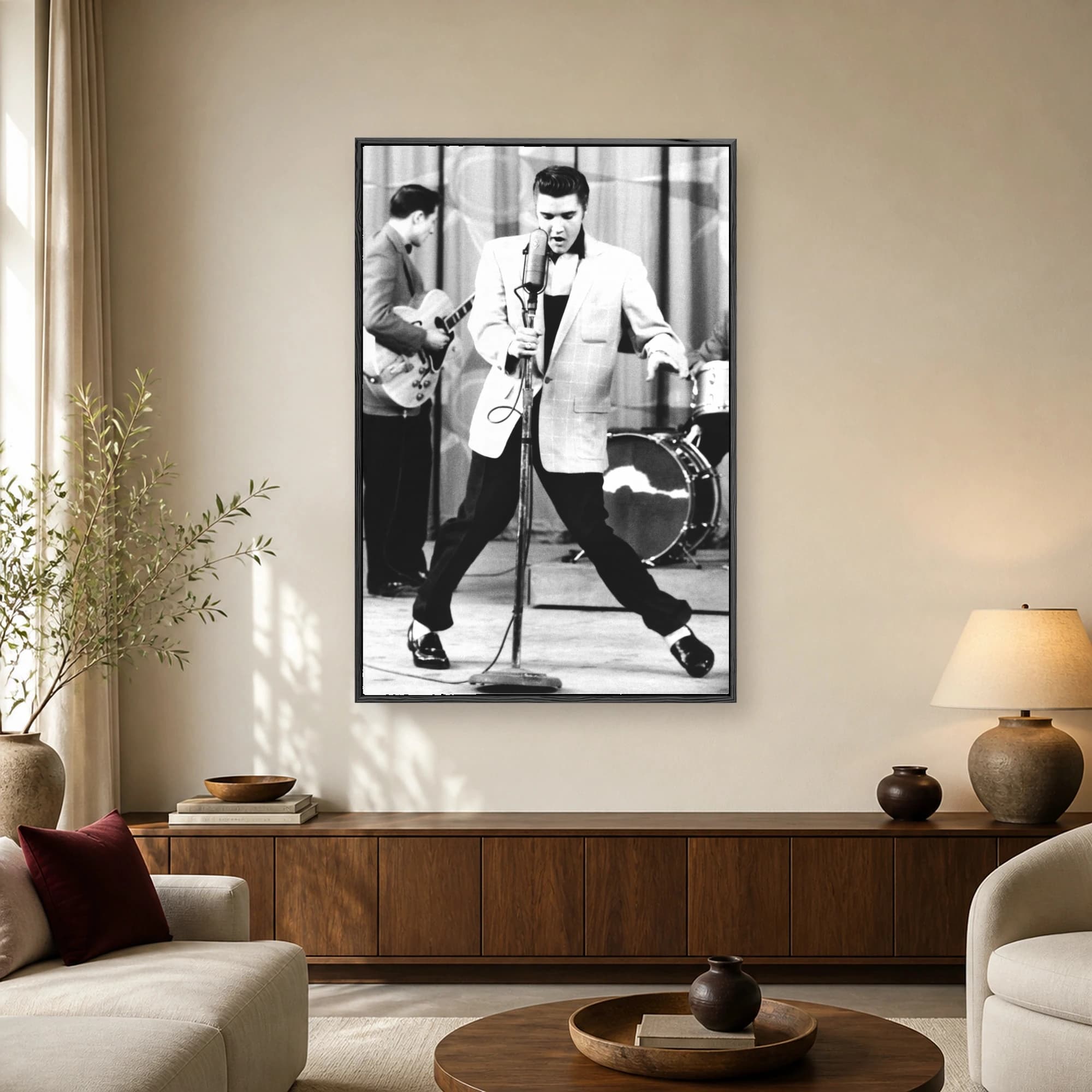 Black and white photograph of Elvis Presley singing into a vintage microphone on stage in his signature wide-legged stance.
