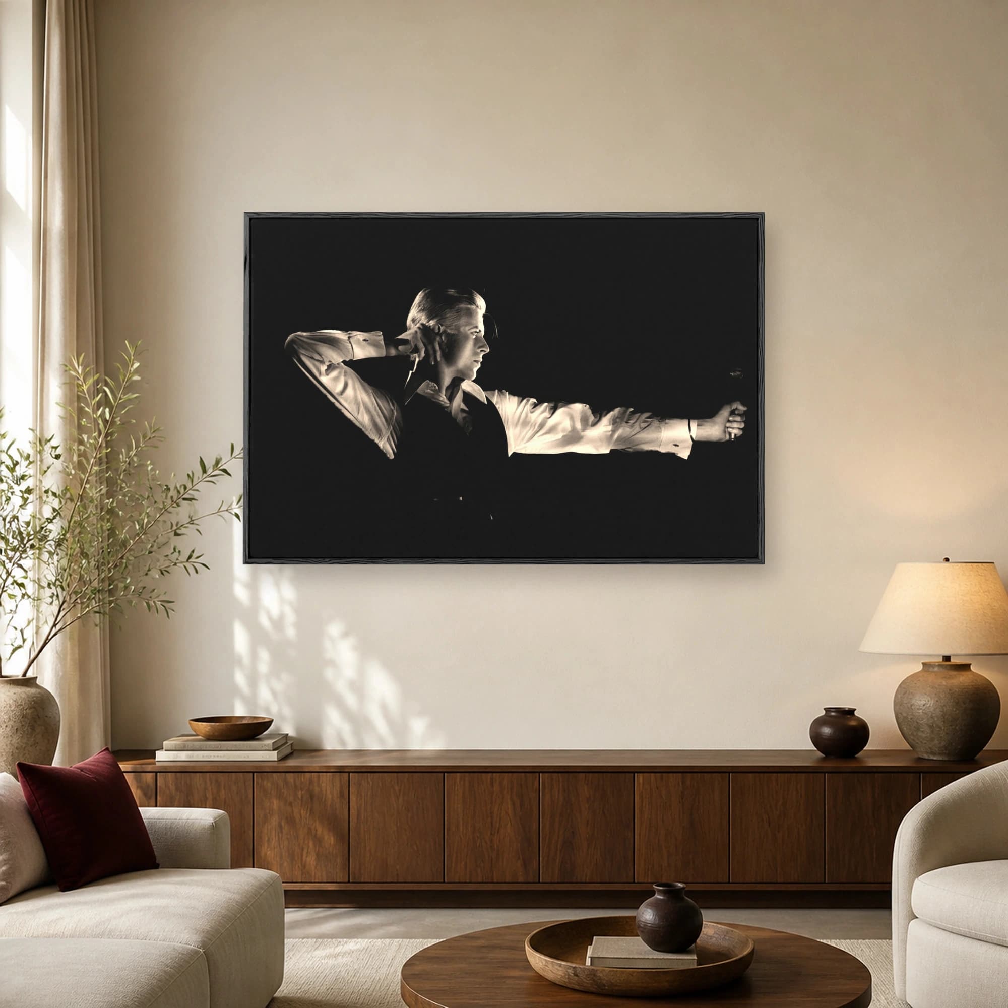 A black and white portrait of David Bowie in a crisp white shirt and vest aiming an arrow in a dramatic pose.