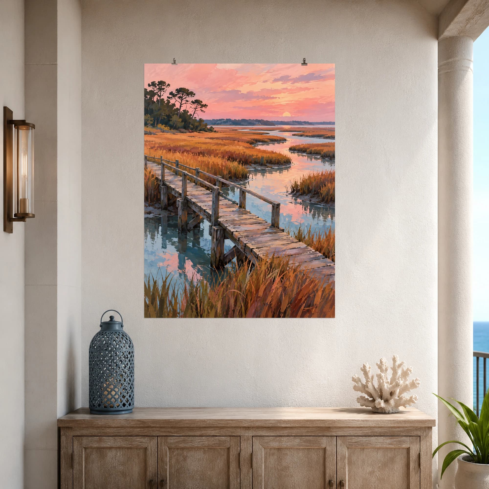 This gouache-style composition features a narrow weathered wooden footbridge over a winding salt marsh creek, copper grasses and pale blue water beneath a soft pink evening sky. Expressive brushwork and a balanced palette bring warmth and character to your space.