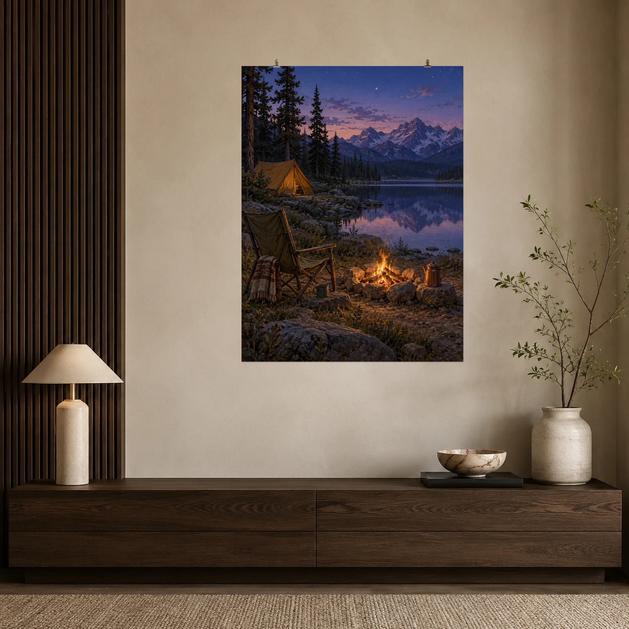 A small lakeside campfire glows beside a canvas chair beneath mountains and the first evening stars.