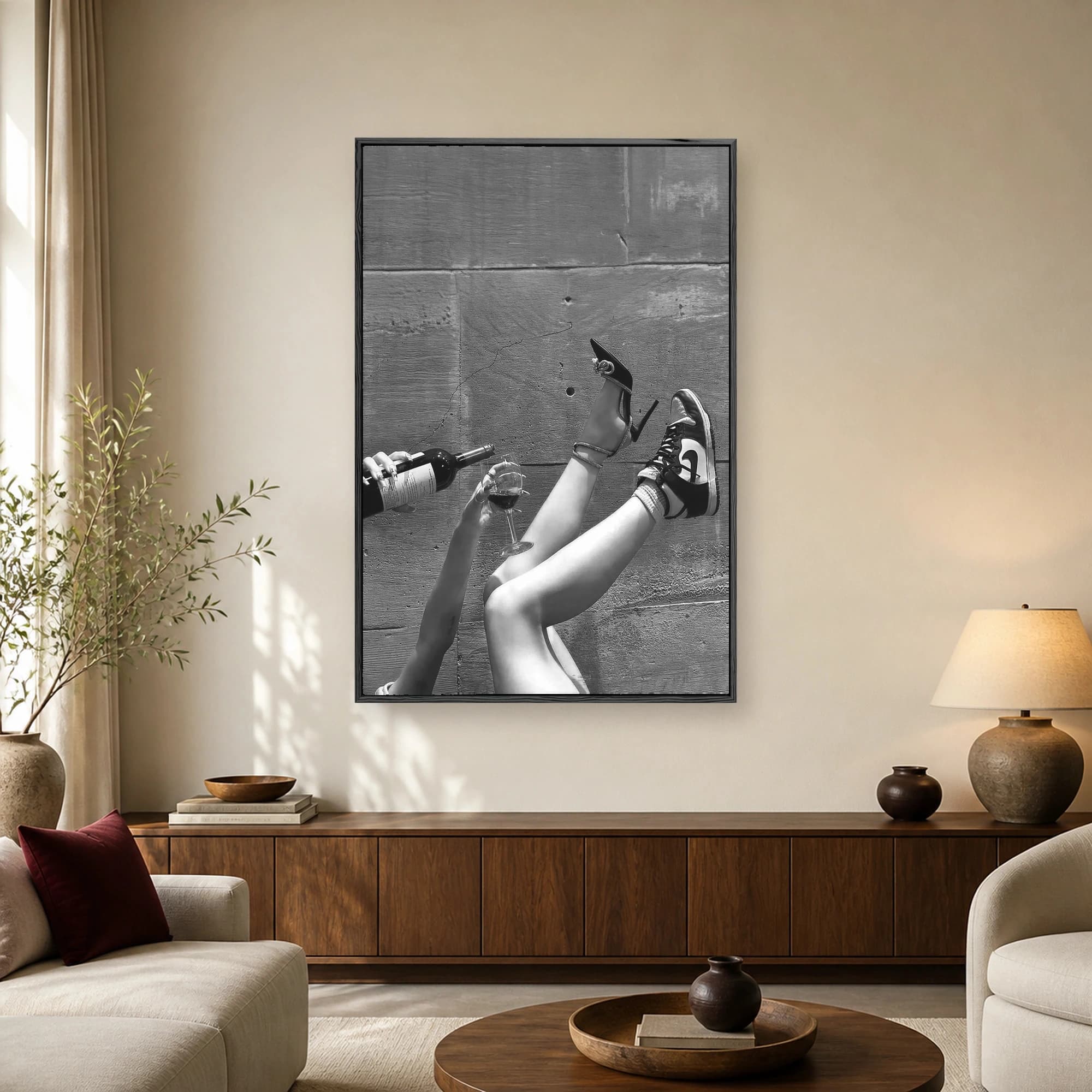 Black and white photograph of legs in the air wearing one stiletto heel and one sneaker, with a hand pouring wine into a glass against a stone wall.