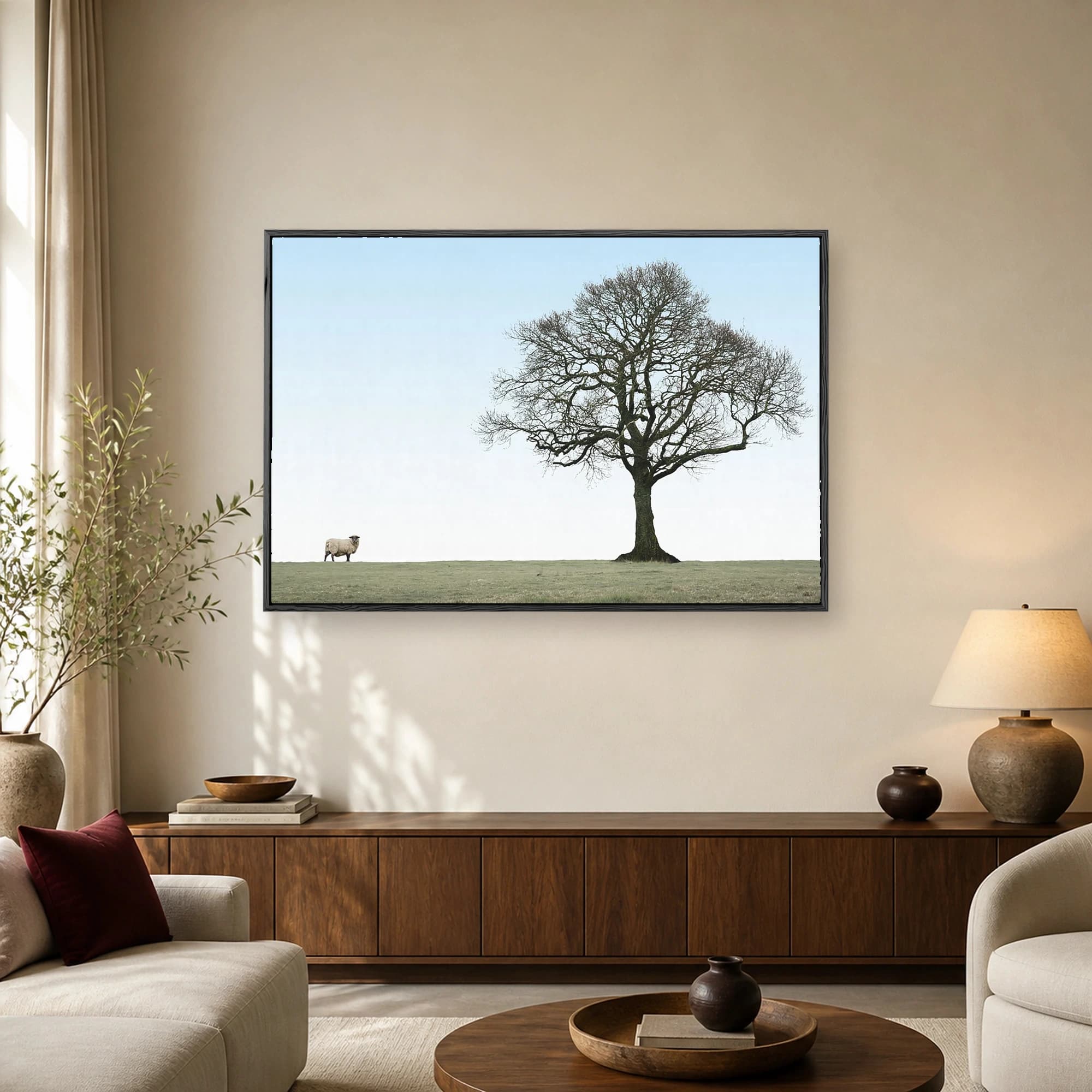 A minimalist landscape photography print showing a sprawling bare tree and a single sheep grazing in a green meadow under a pale blue sky.