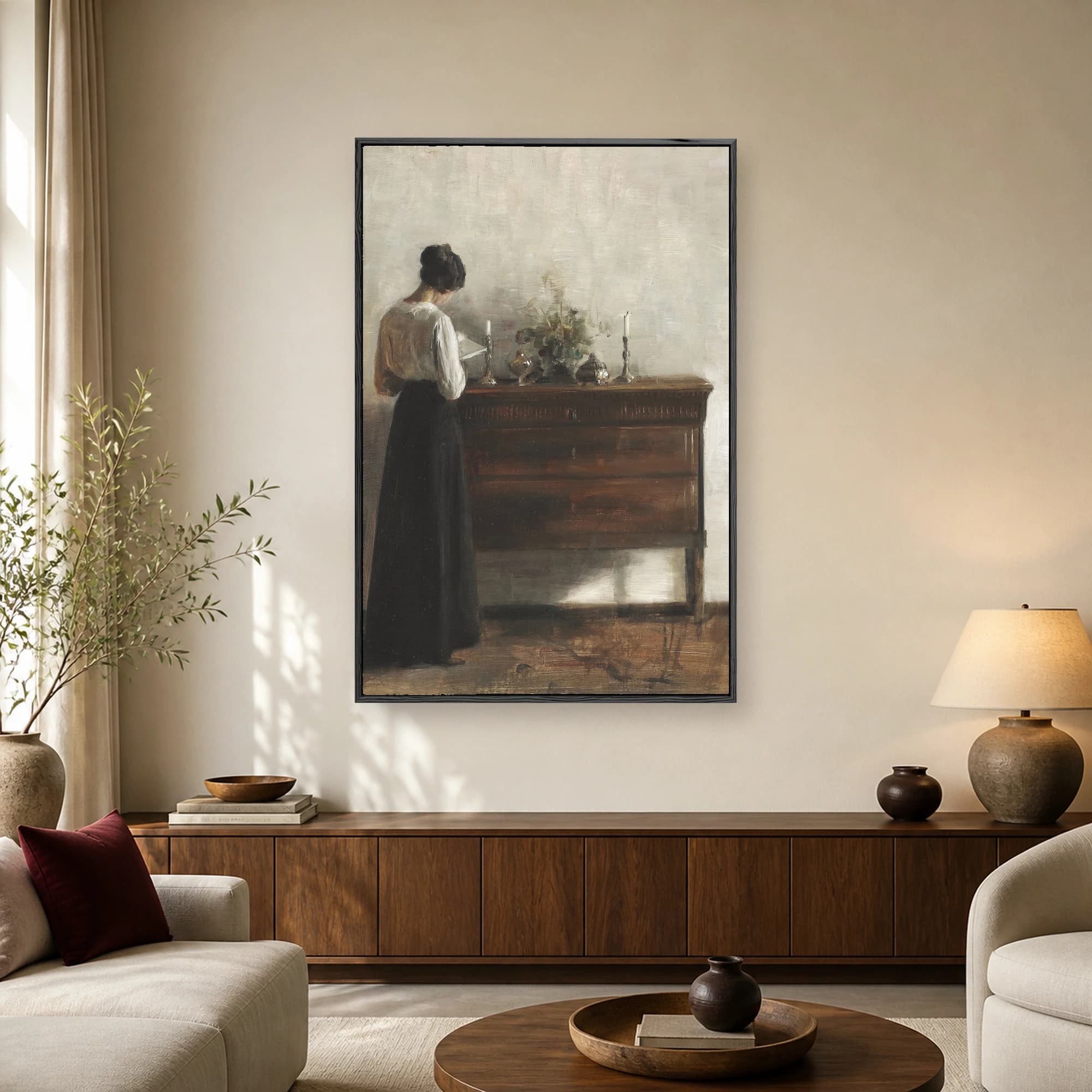 Fine art painting of a woman in a white blouse and dark skirt reading by an antique wooden dresser with candlesticks against a neutral wall.