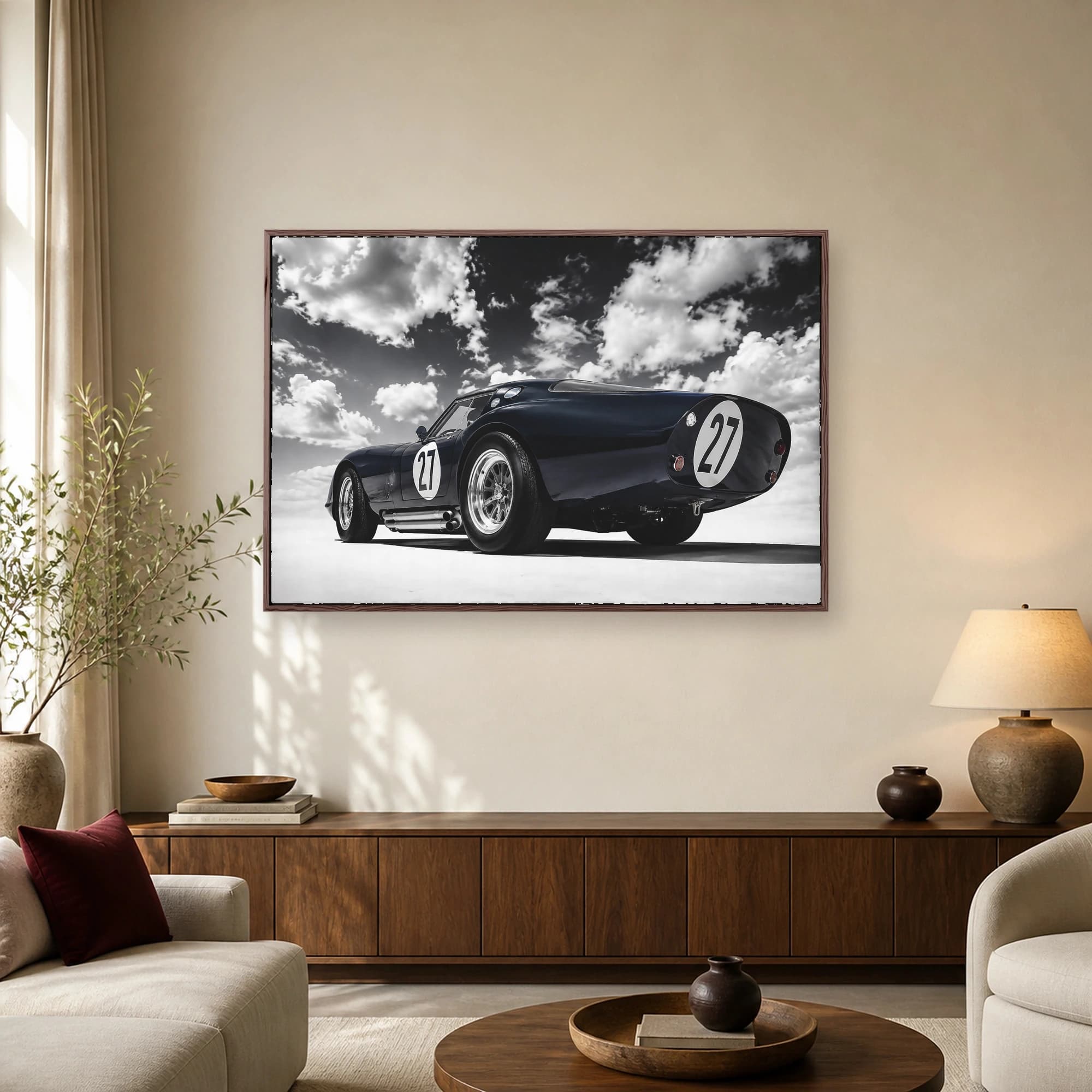 Low angle view of a dark blue vintage racing coupe with number 27 roundels under a dramatic cloudy sky.