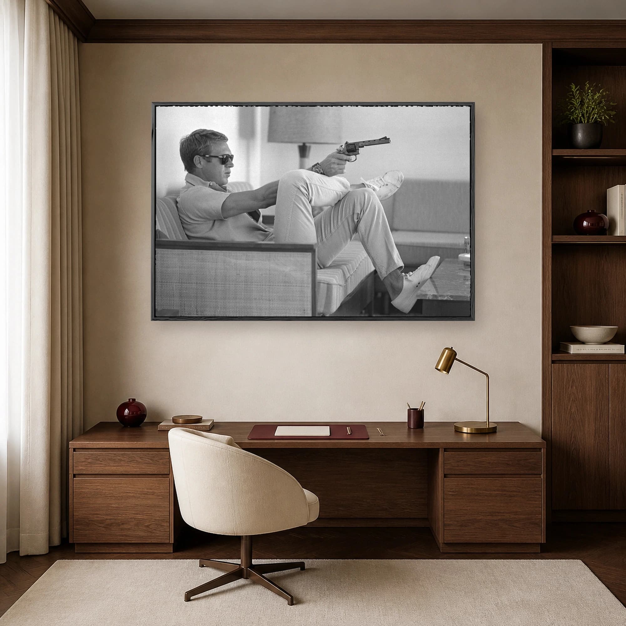 Black and white photograph of actor Steve McQueen wearing sunglasses and sneakers while relaxing on a sofa and holding a revolver.
