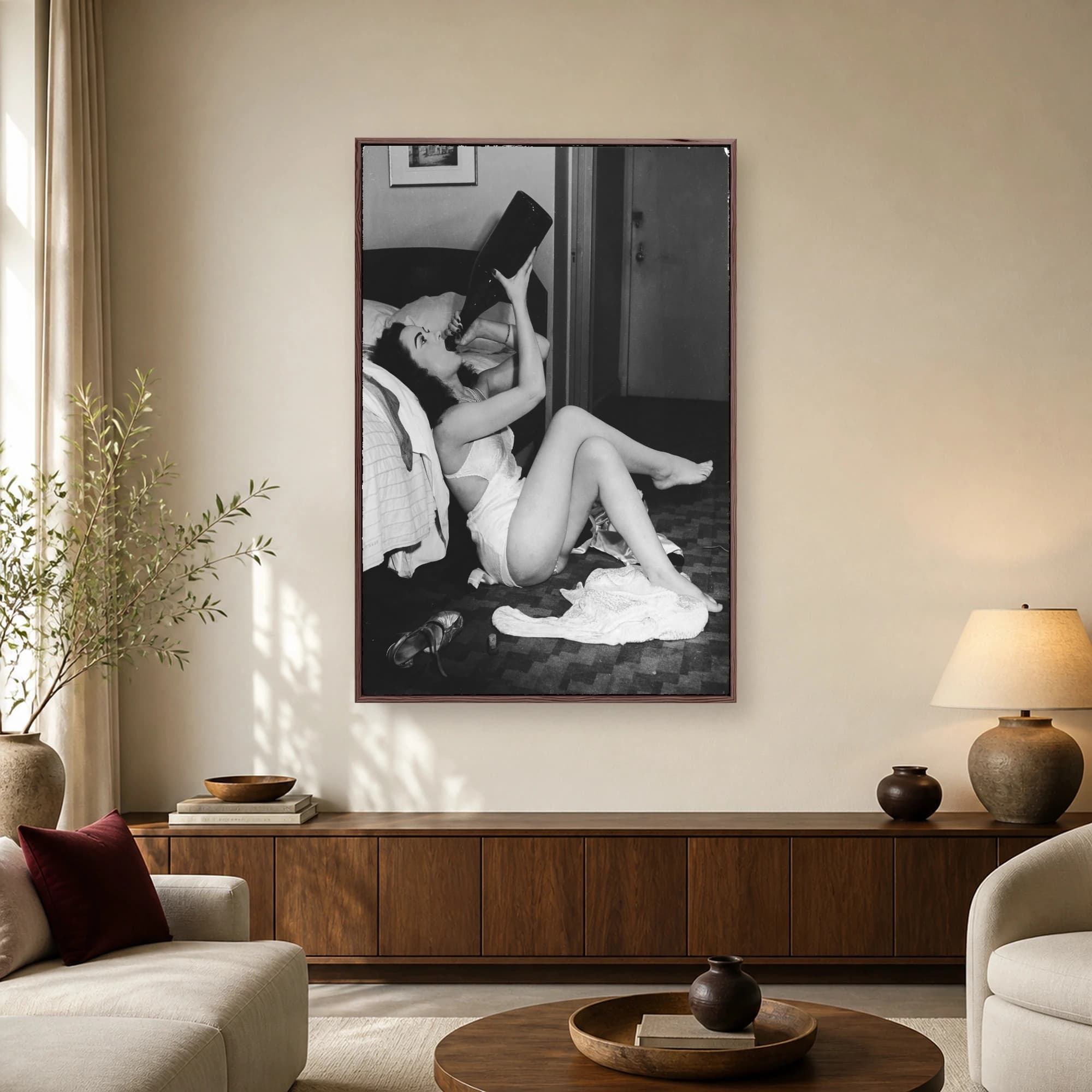 Vintage black and white photograph of a Hollywood starlet in satin lingerie drinking from an oversized bottle on the floor.