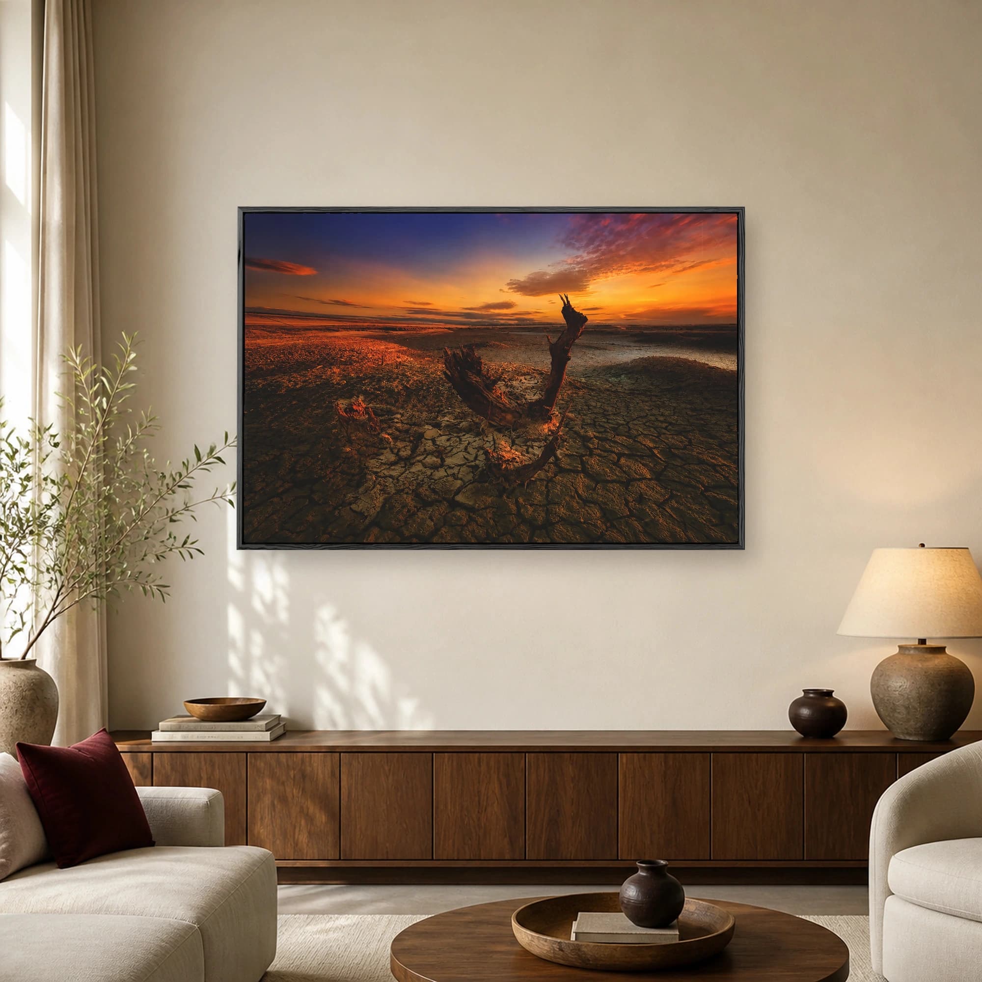 A desolate landscape of cracked mud featuring a weathered tree stump under a vibrant orange and blue sunset sky.