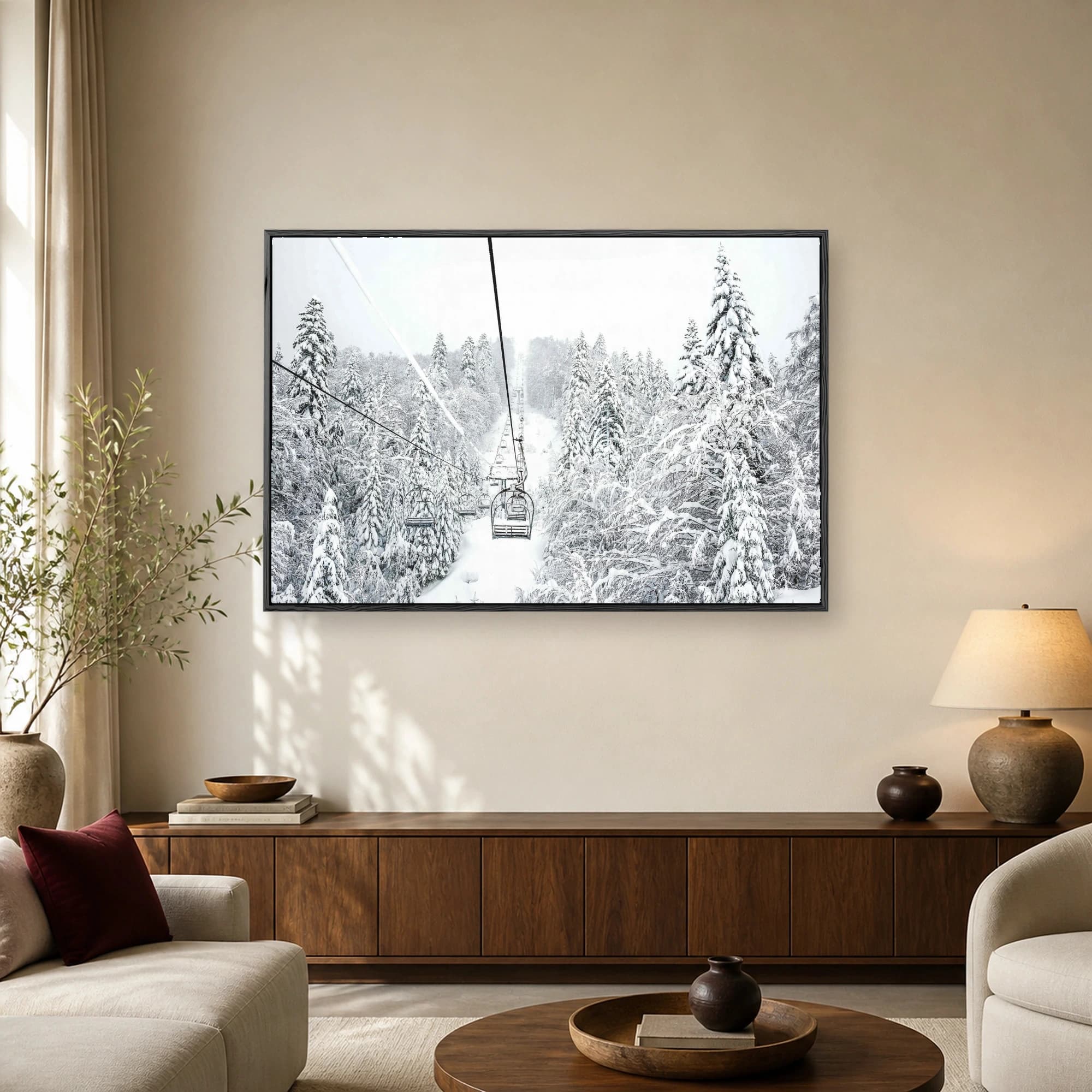 A black and white winter photograph looking up a ski lift line through a forest of heavy snow-covered pine trees.