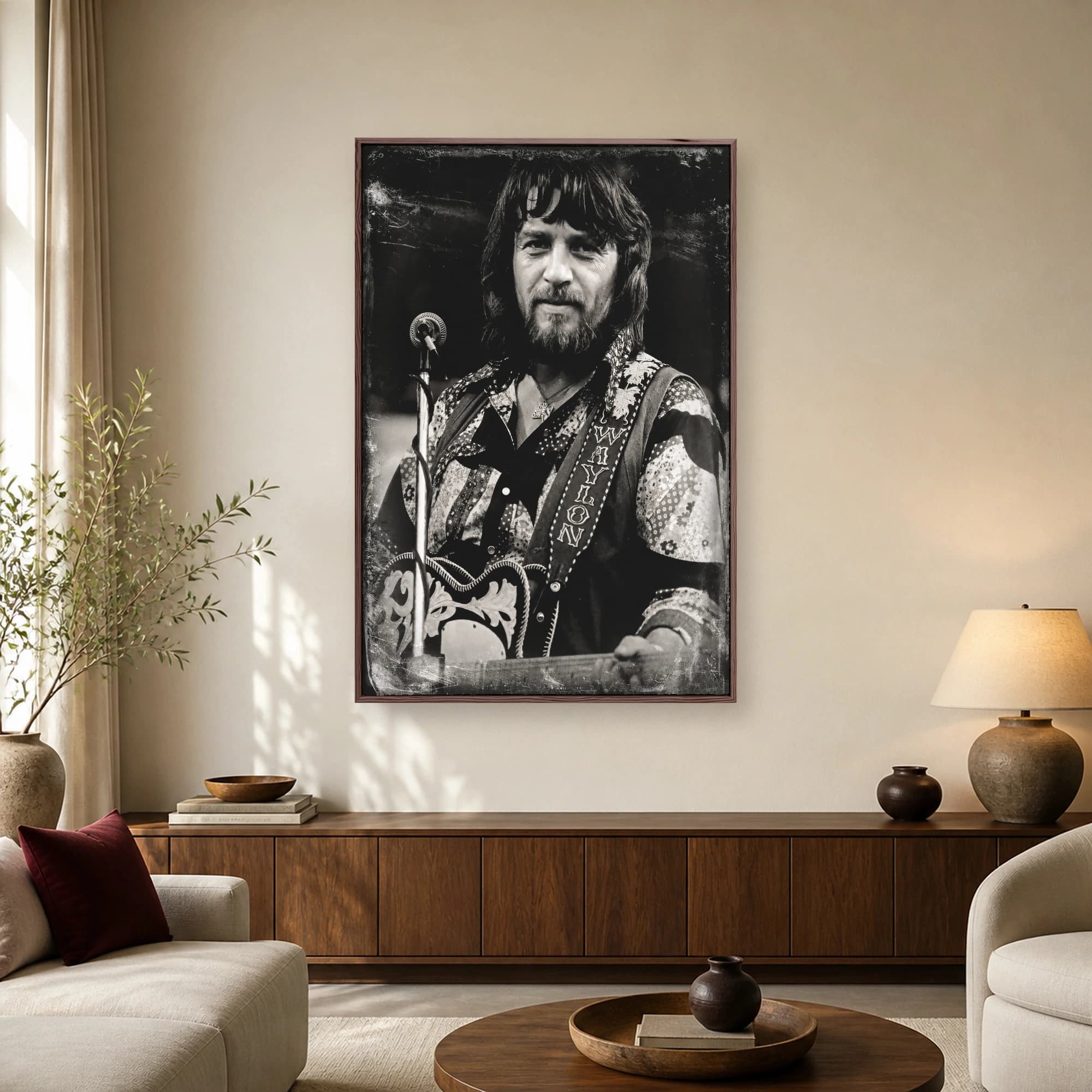 Black and white portrait of country music legend Waylon Jennings holding a guitar with an embroidered strap next to a microphone stand, featuring distressed vintage photographic