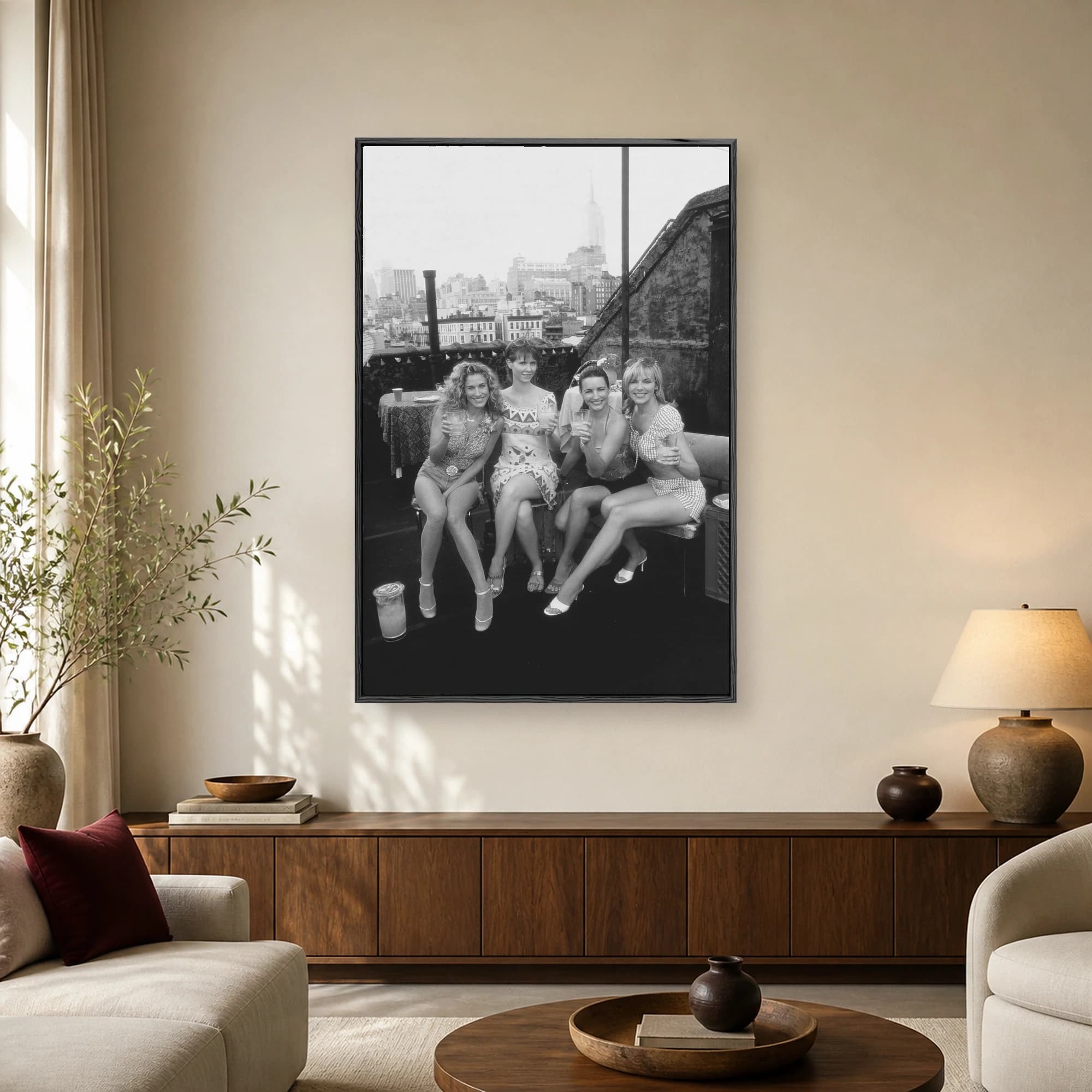 Black and white photograph of the four main female characters from Sex and the City toasting with drinks on a New York City rooftop.