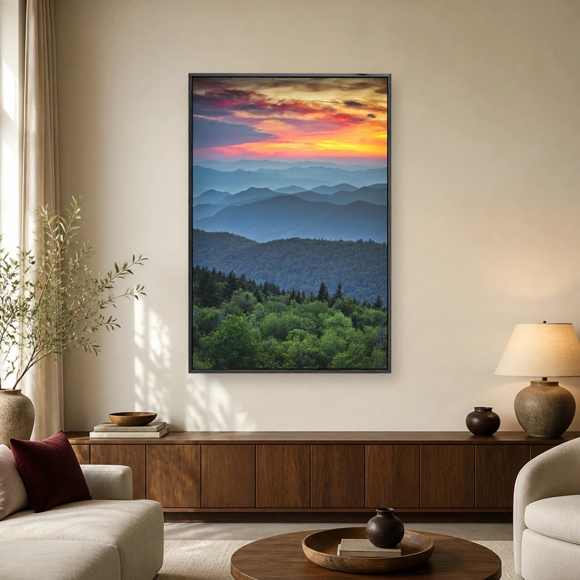 Vertical fine art photograph of layered blue mountain ridges under a vibrant orange and purple sunset sky above a dark green pine forest.