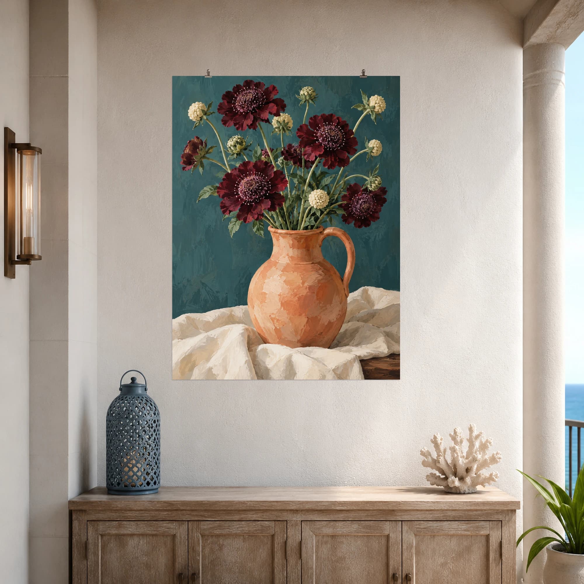 This gouache-style composition features airy burgundy scabiosa flowers and pale cream buds in an apricot earthenware jug, teal wall and folded ivory linen. Expressive brushwork and a balanced palette bring warmth and character to your space.