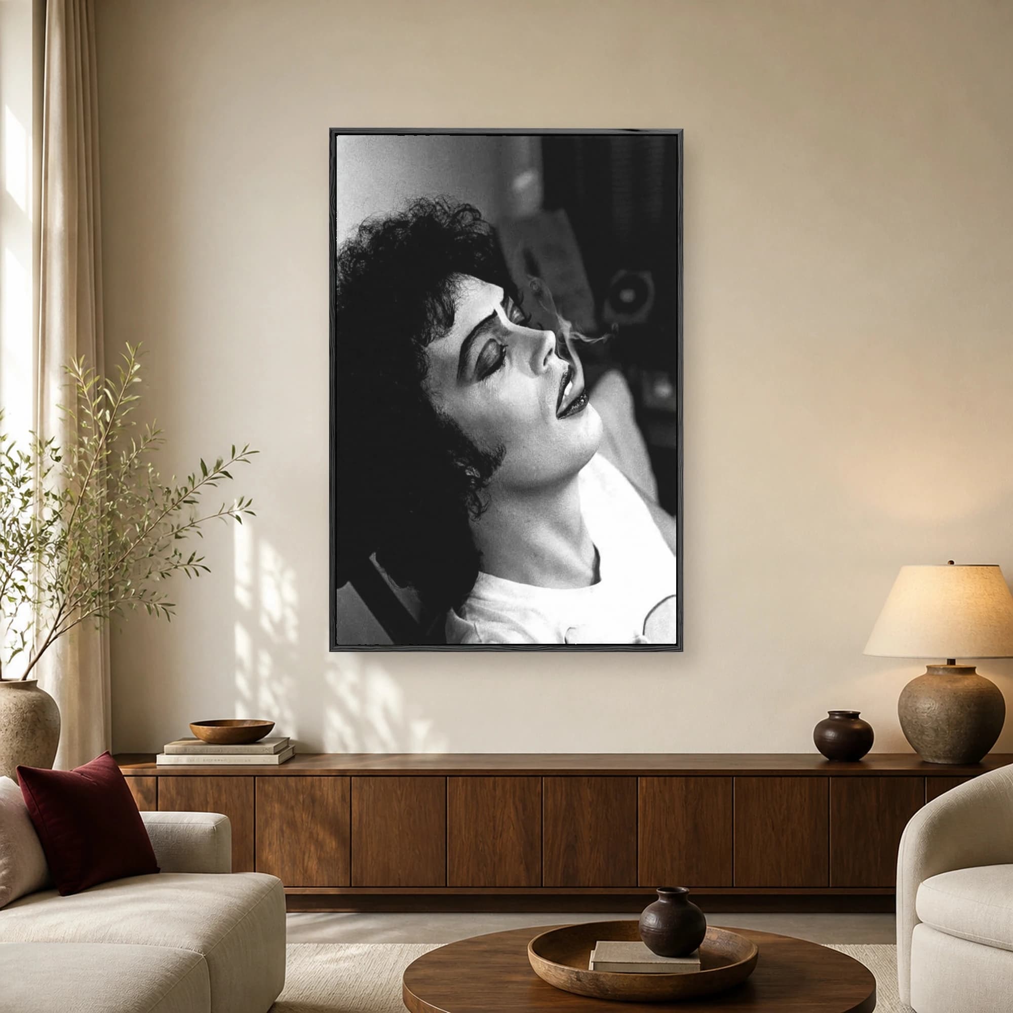Black and white portrait of actor Tim Curry with dark curly hair and theatrical makeup, exhaling cigarette smoke in profile view.
