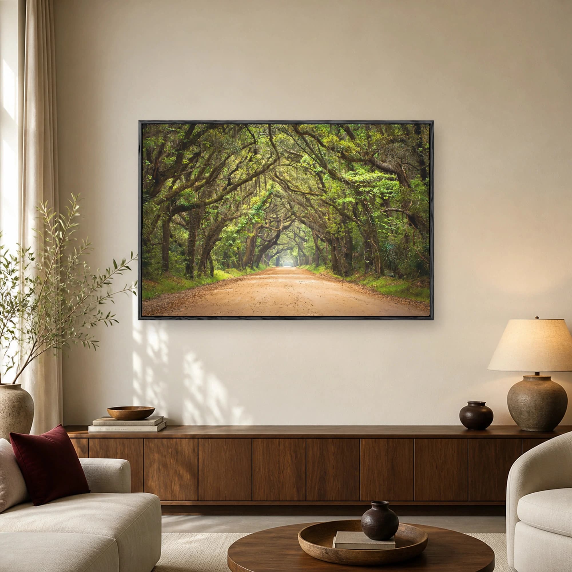 Sunlit dirt road winding under a dense canopy of ancient live oak trees draped with Spanish moss, forming a natural green tunnel.