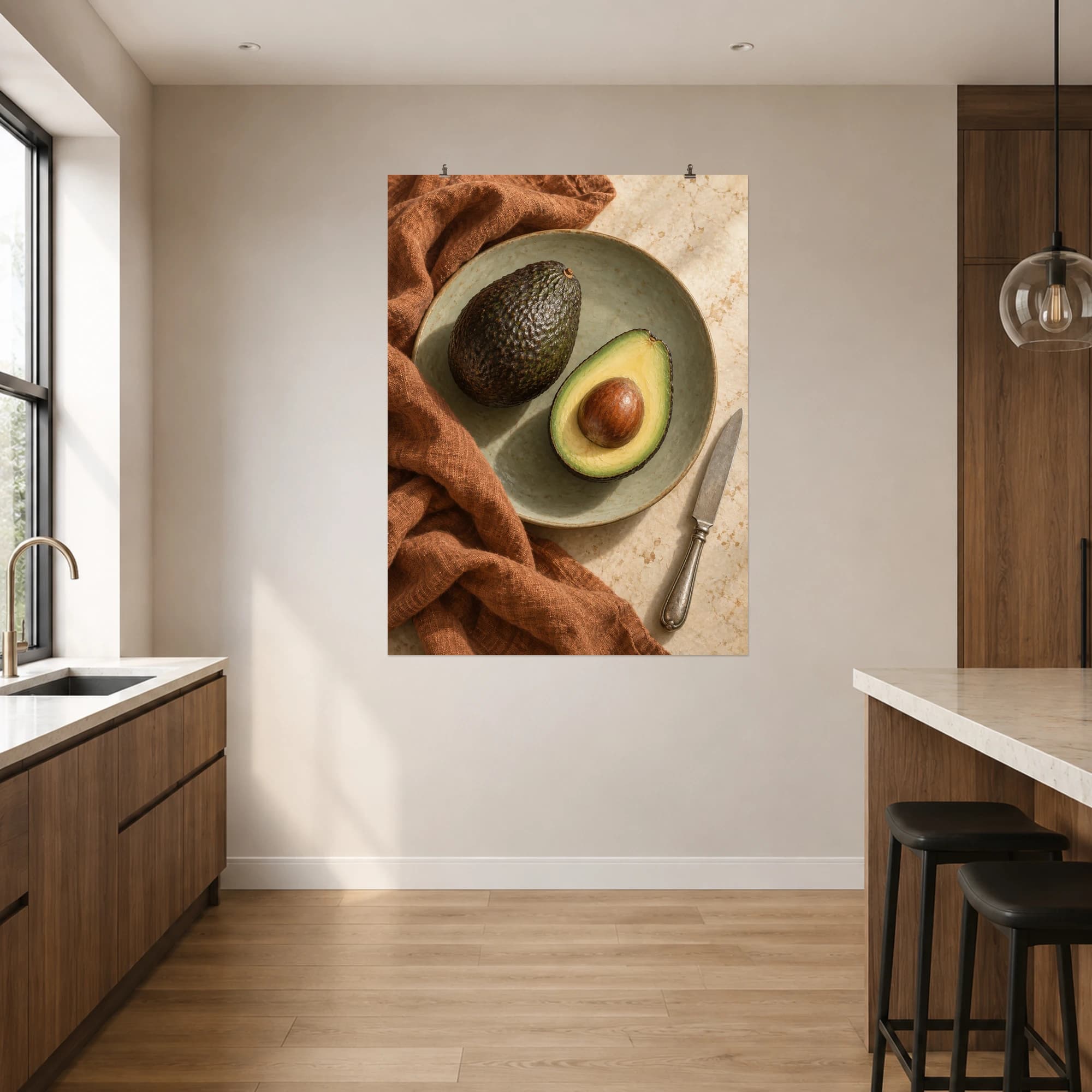 A ripe avocado and its cut half rest on a sage ceramic plate beside warm linen.
