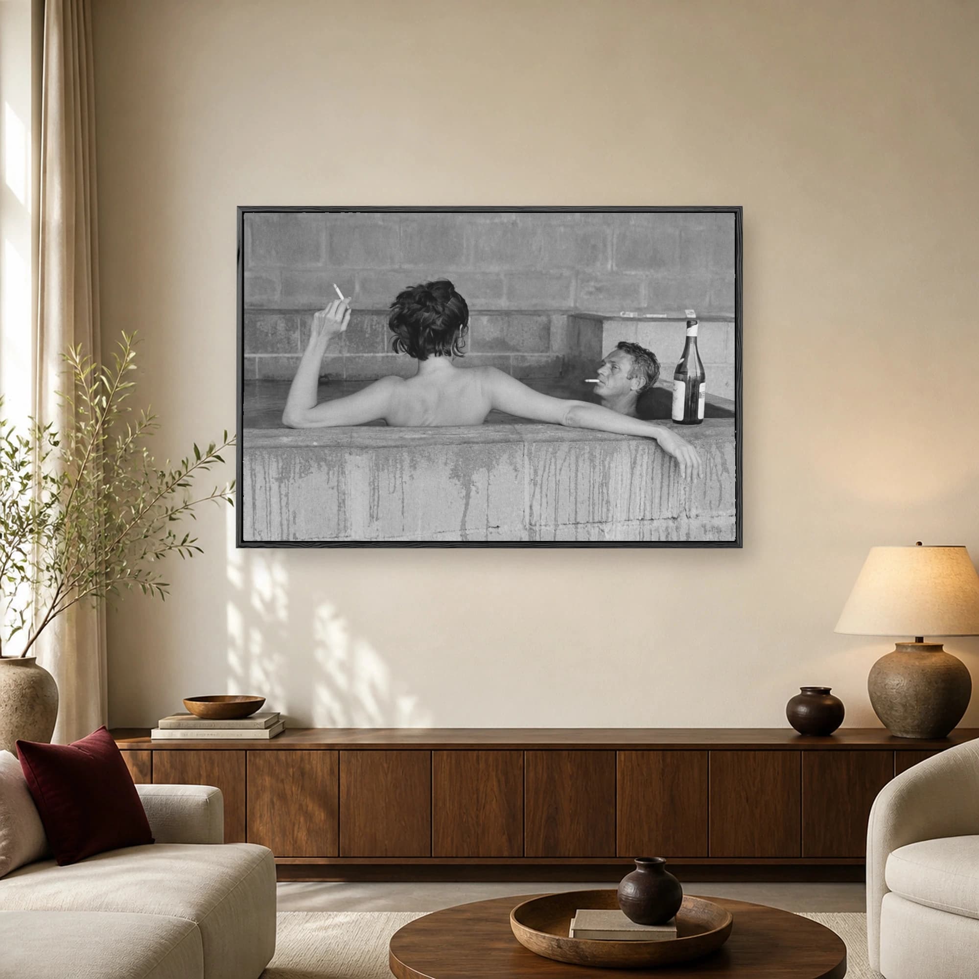 Black and white vintage photo of actor Steve McQueen and Neile Adams relaxing in a concrete hot tub with cigarettes and a wine bottle.