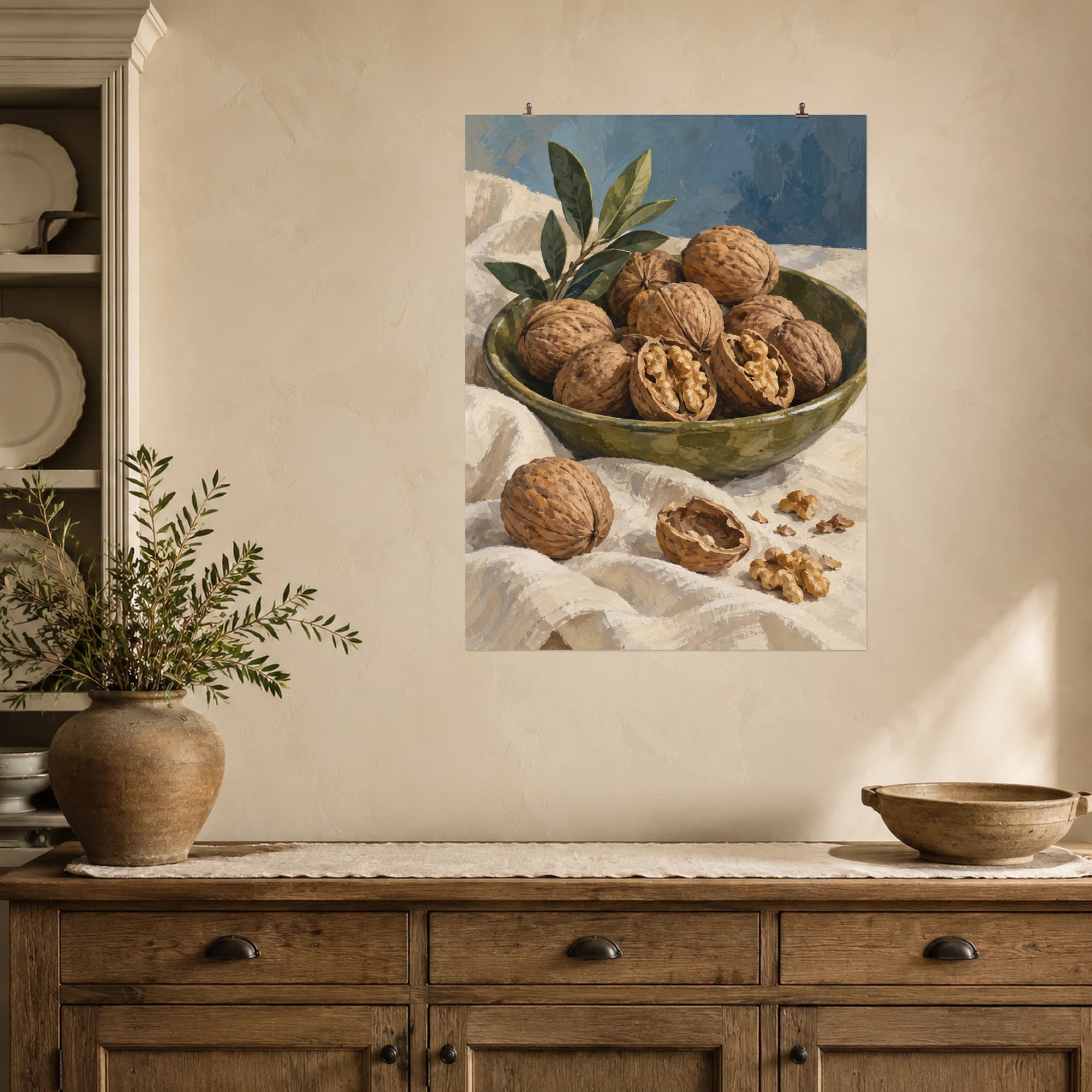 Whole walnuts and open halves rest in a shallow olive dish. Cream linen and a muted blue backdrop give this harvest still life a warm, understated character.