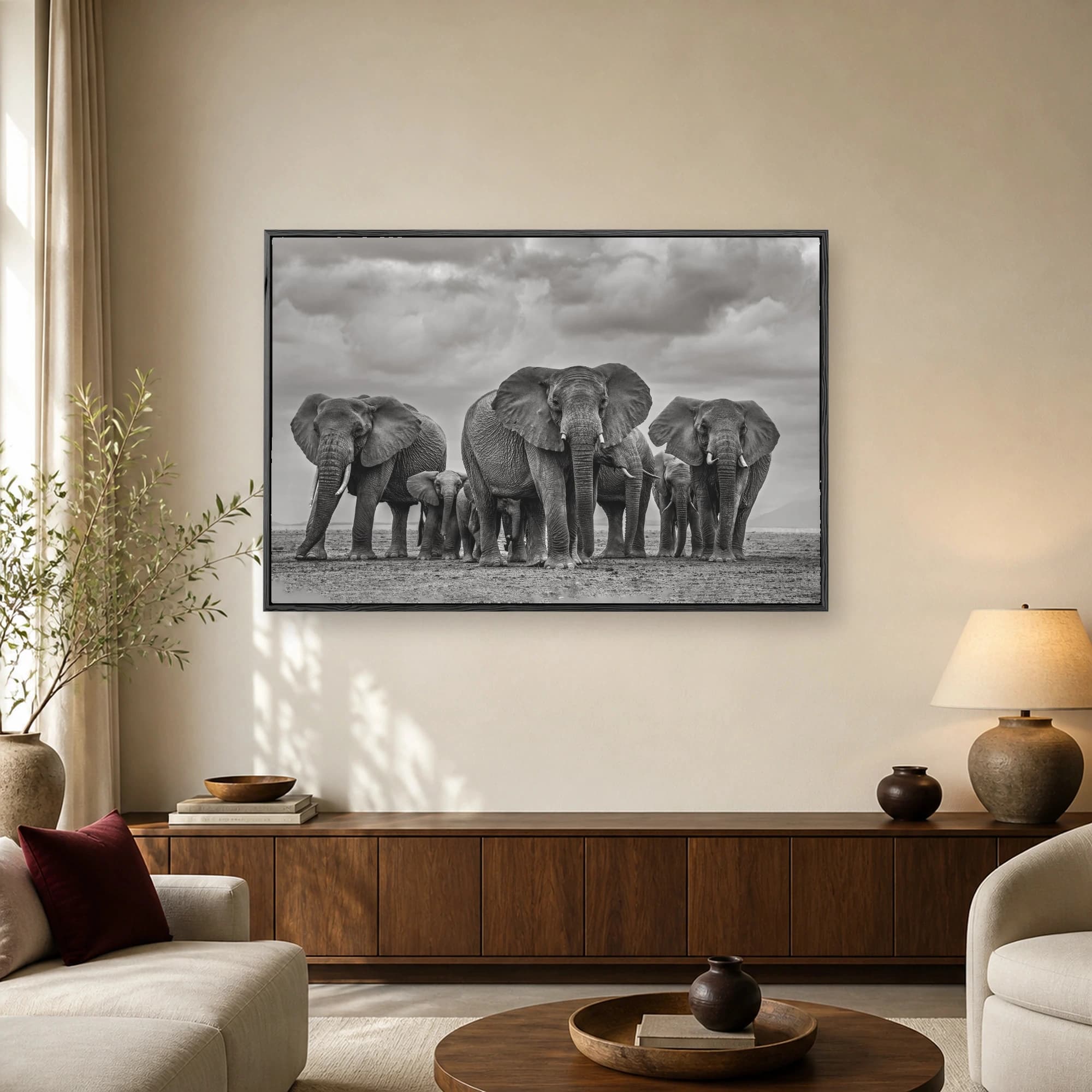 Fine art black and white photograph of a herd of African elephants standing together on a plain under a dramatic cloudy sky.