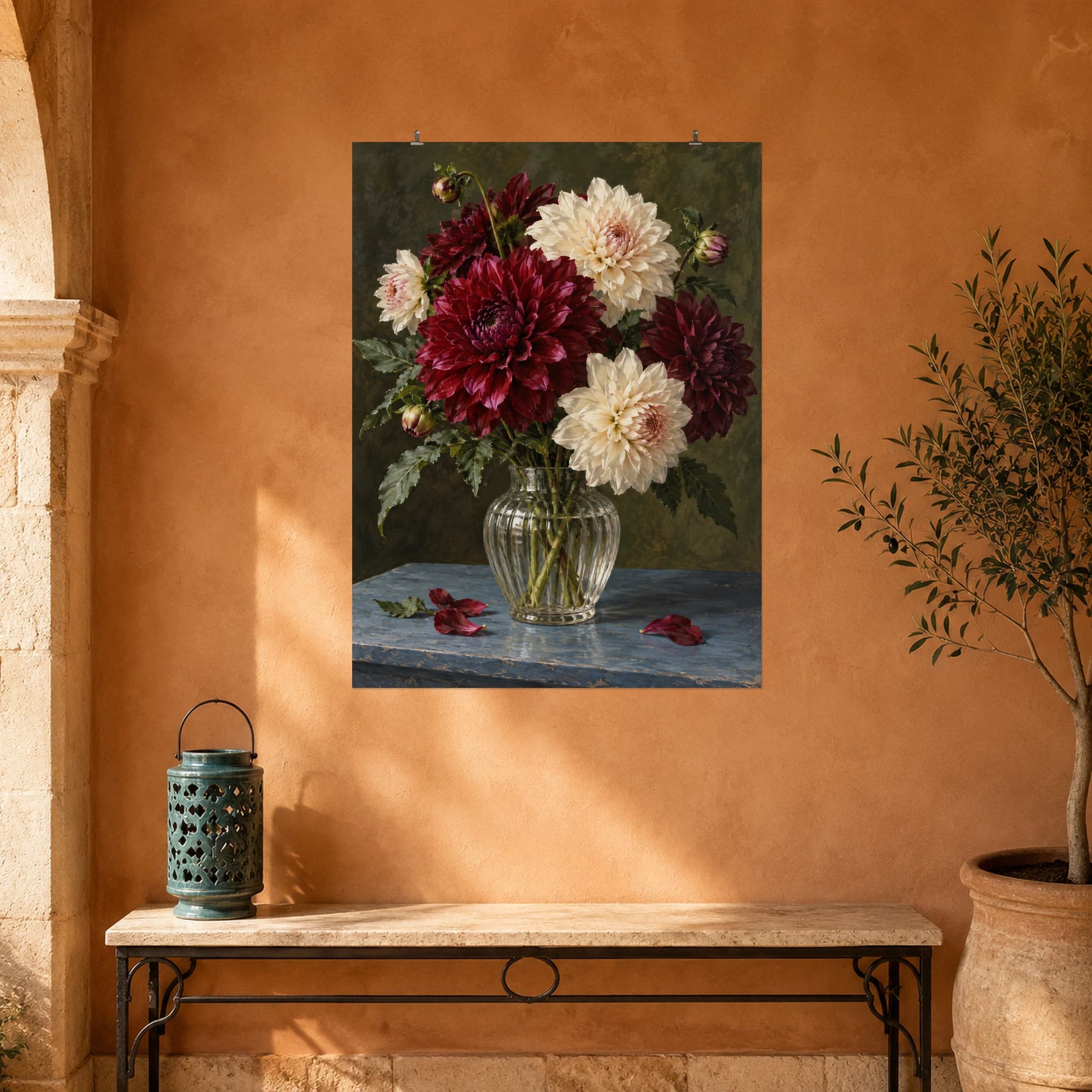 Burgundy and cream dahlias fill a ribbed glass vase on a blue table. A deep olive backdrop gives the arrangement a rich, intimate mood.
