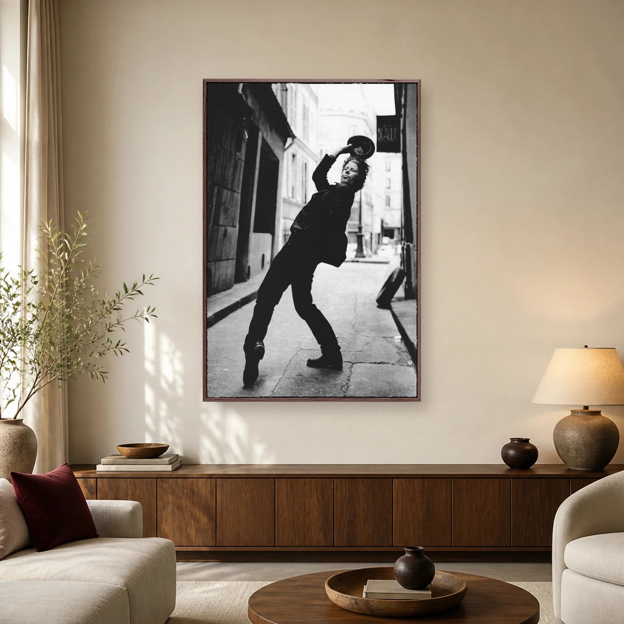 Black and white portrait of musician Tom Waits leaning backwards dramatically in an alleyway while lifting a hat above his head.