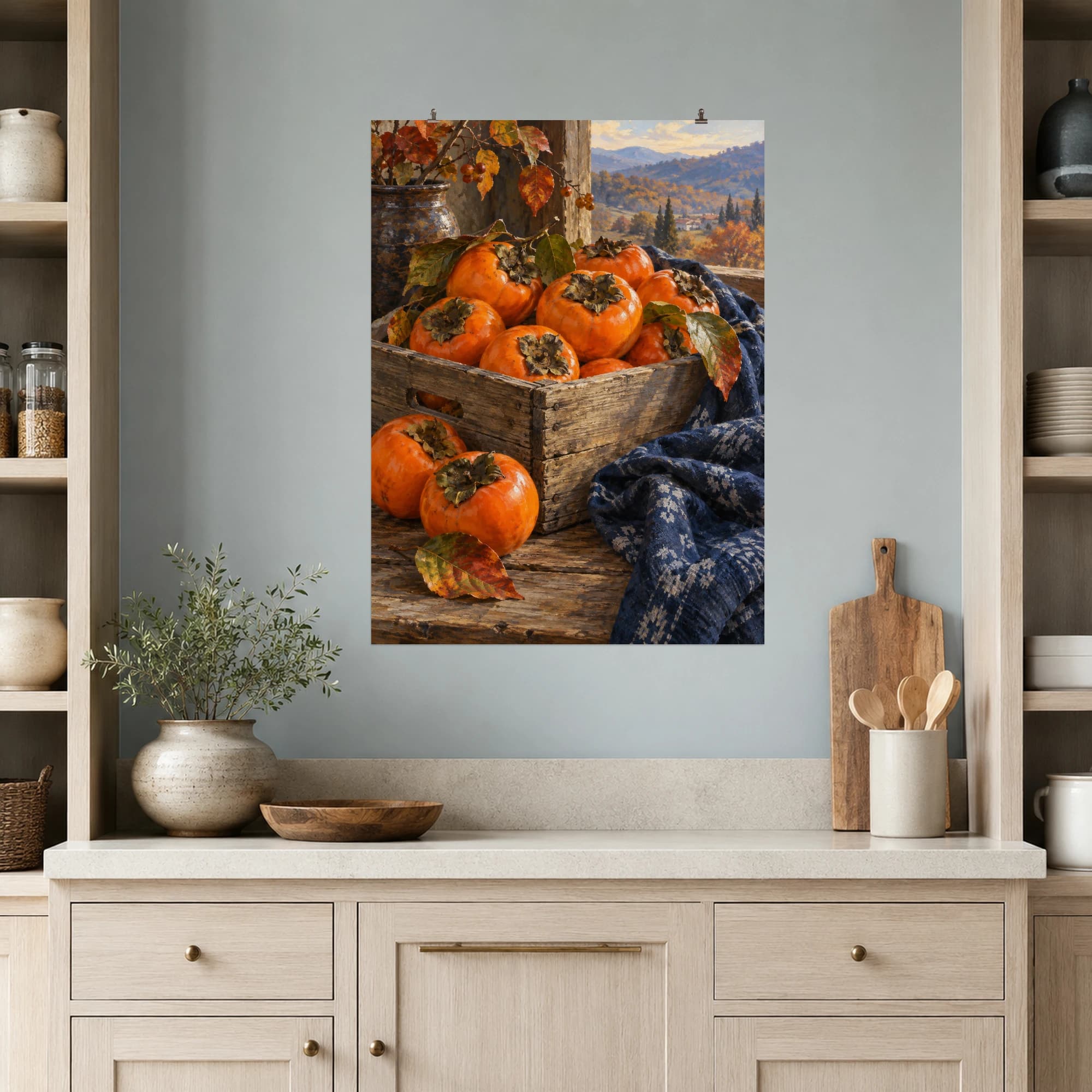 Ripe persimmons fill a wooden crate beside indigo cloth. Autumn window light draws out the fruit's warm orange color.