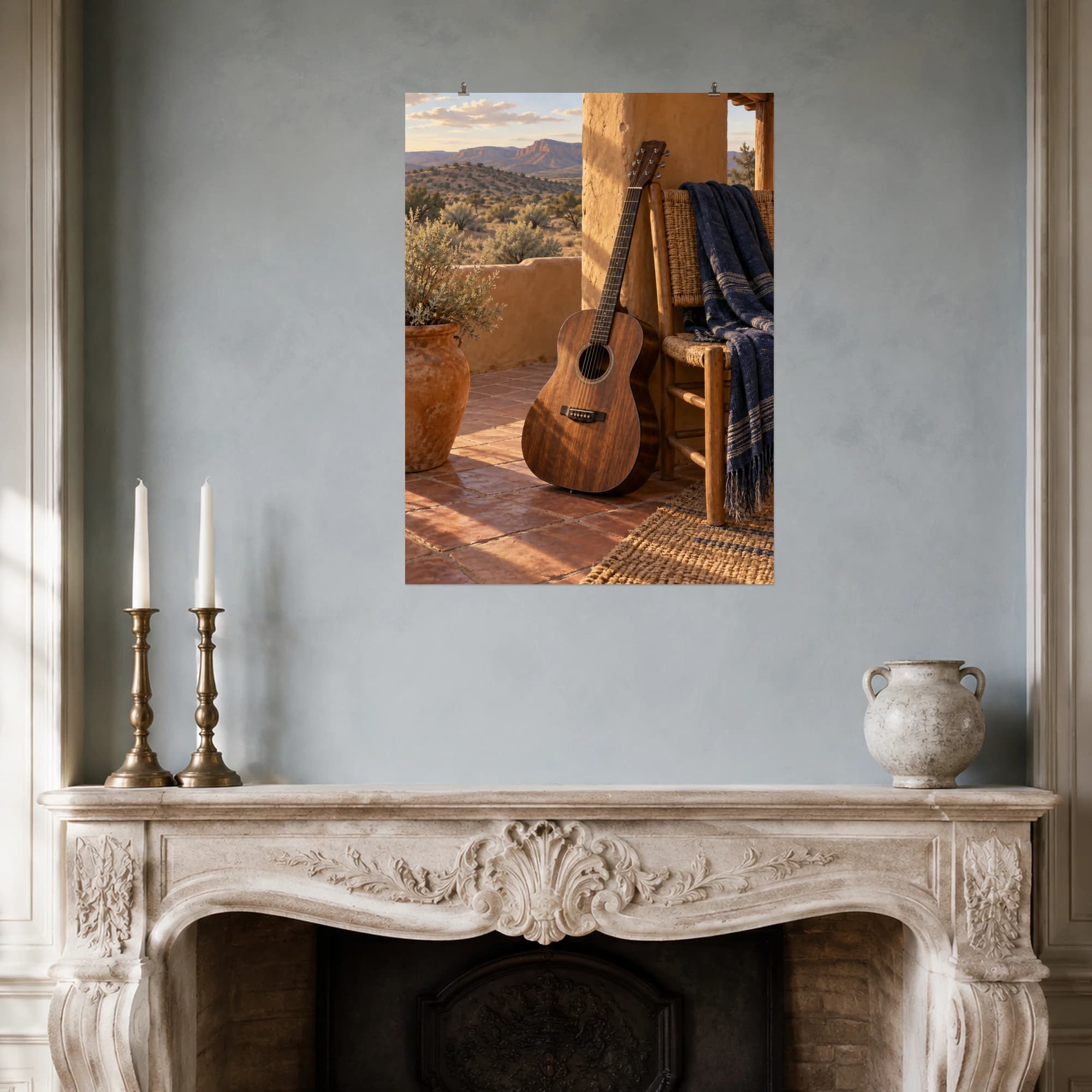 A walnut acoustic guitar leans beside a woven chair on an adobe porch overlooking quiet desert hills.