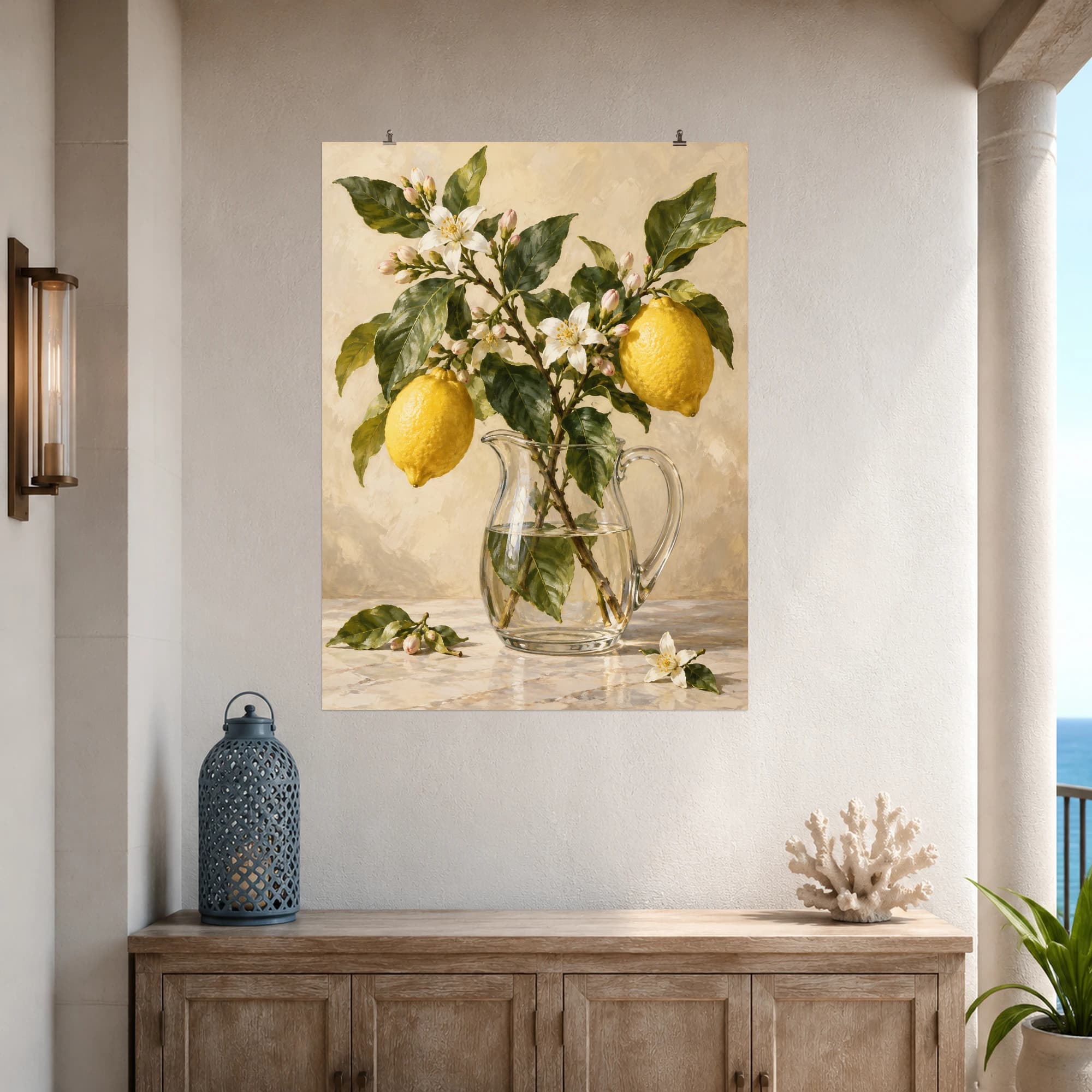 Lemons and pale blossoms share a branch arranged in a clear pitcher. Creamy light and fresh green leaves give the still life a gentle citrus palette.