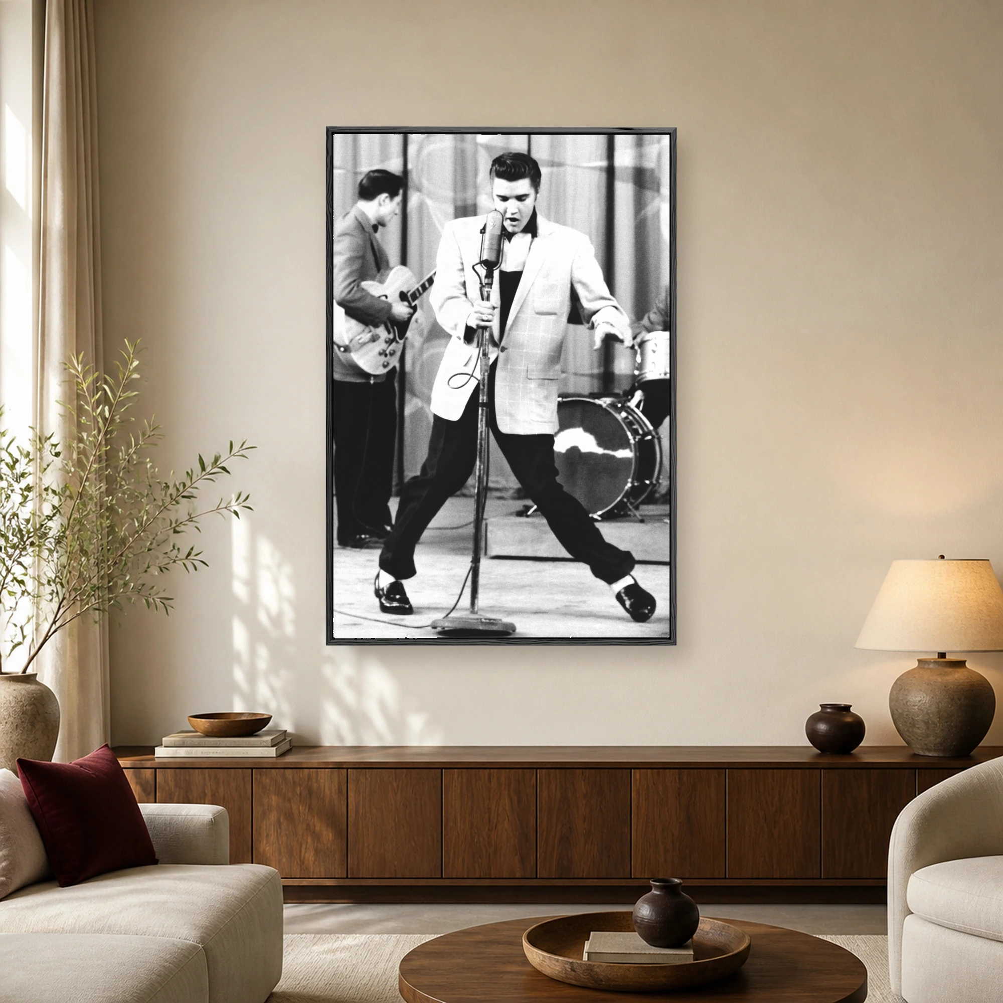 Black and white photograph of Elvis Presley singing into a vintage microphone on stage in his signature wide-legged stance.
