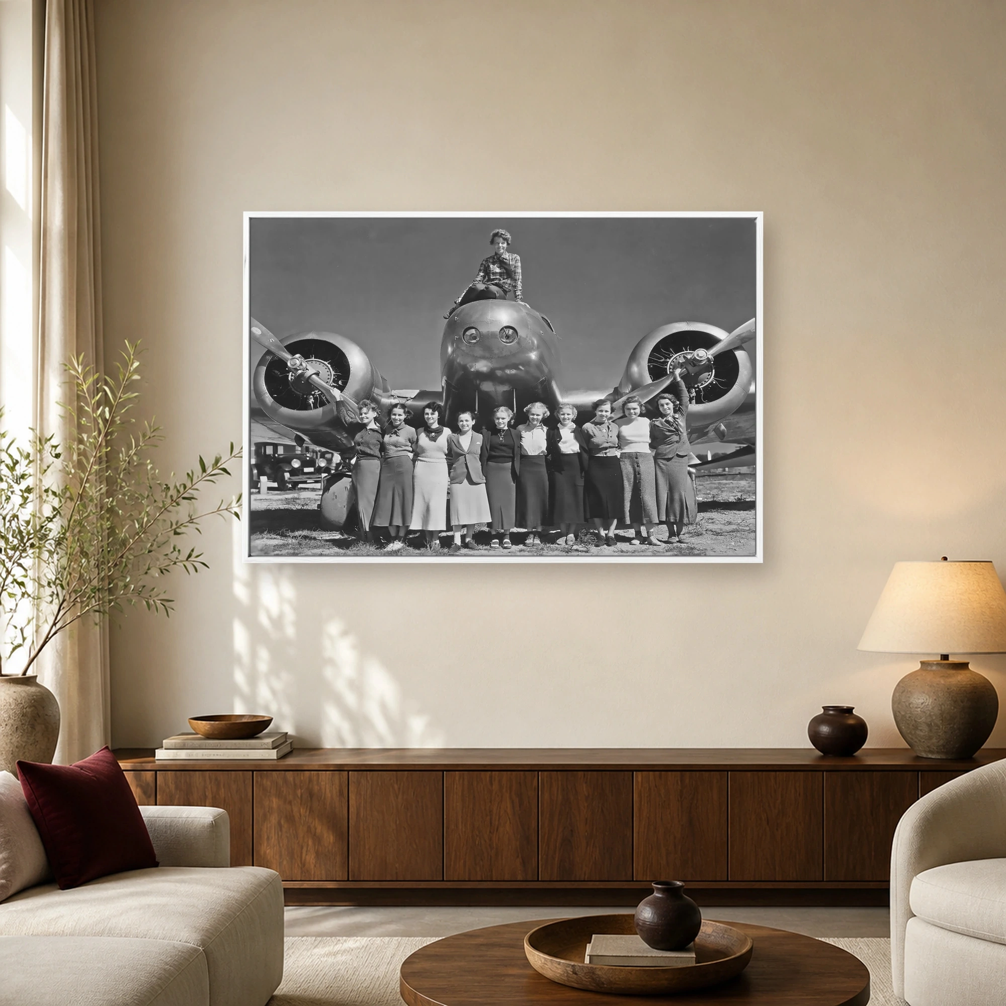 Historic black and white photograph of Amelia Earhart sitting on an airplane nose with members of the Women's Air Reserve.