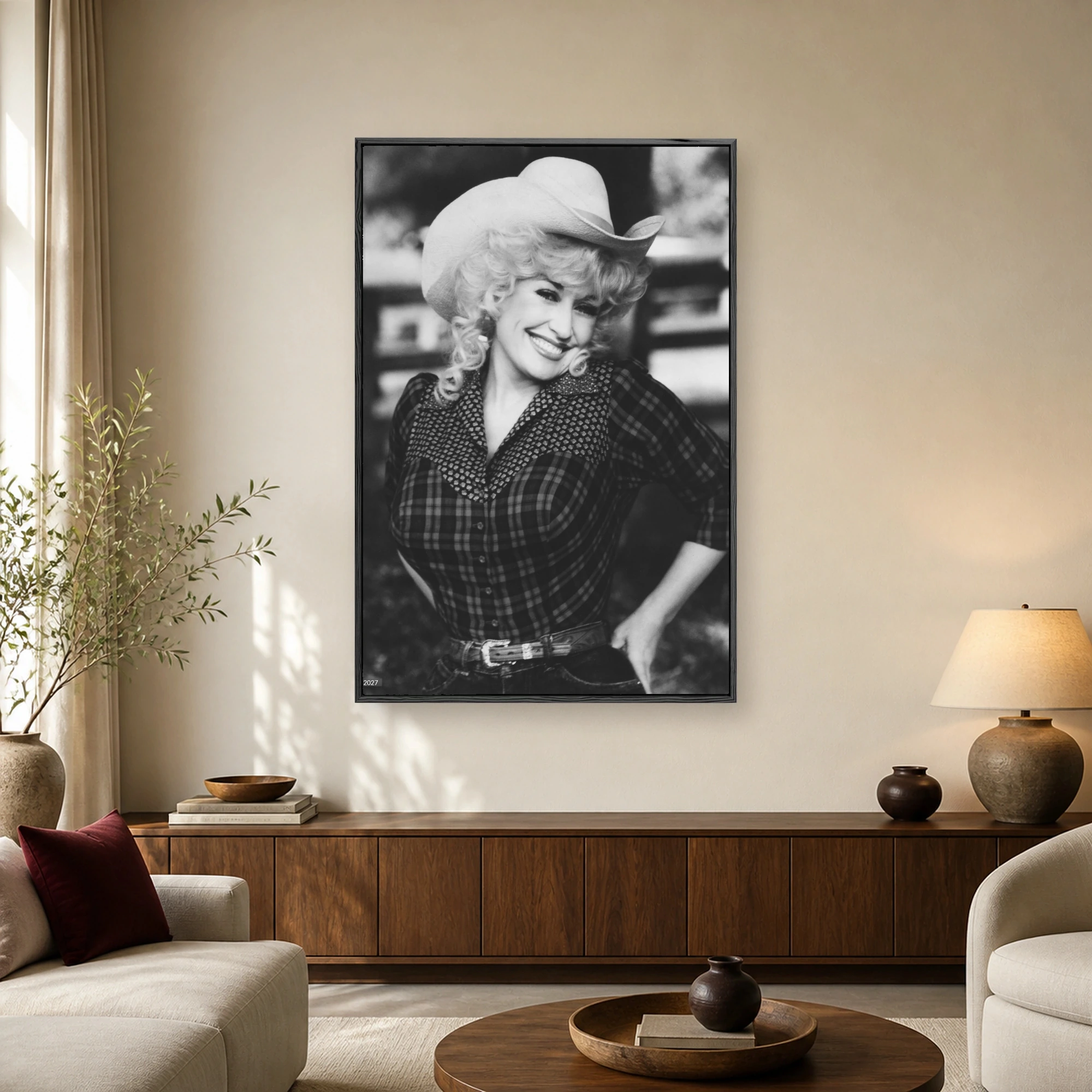 Black and white portrait of Dolly Parton wearing a cowboy hat and plaid shirt while smiling warmly.