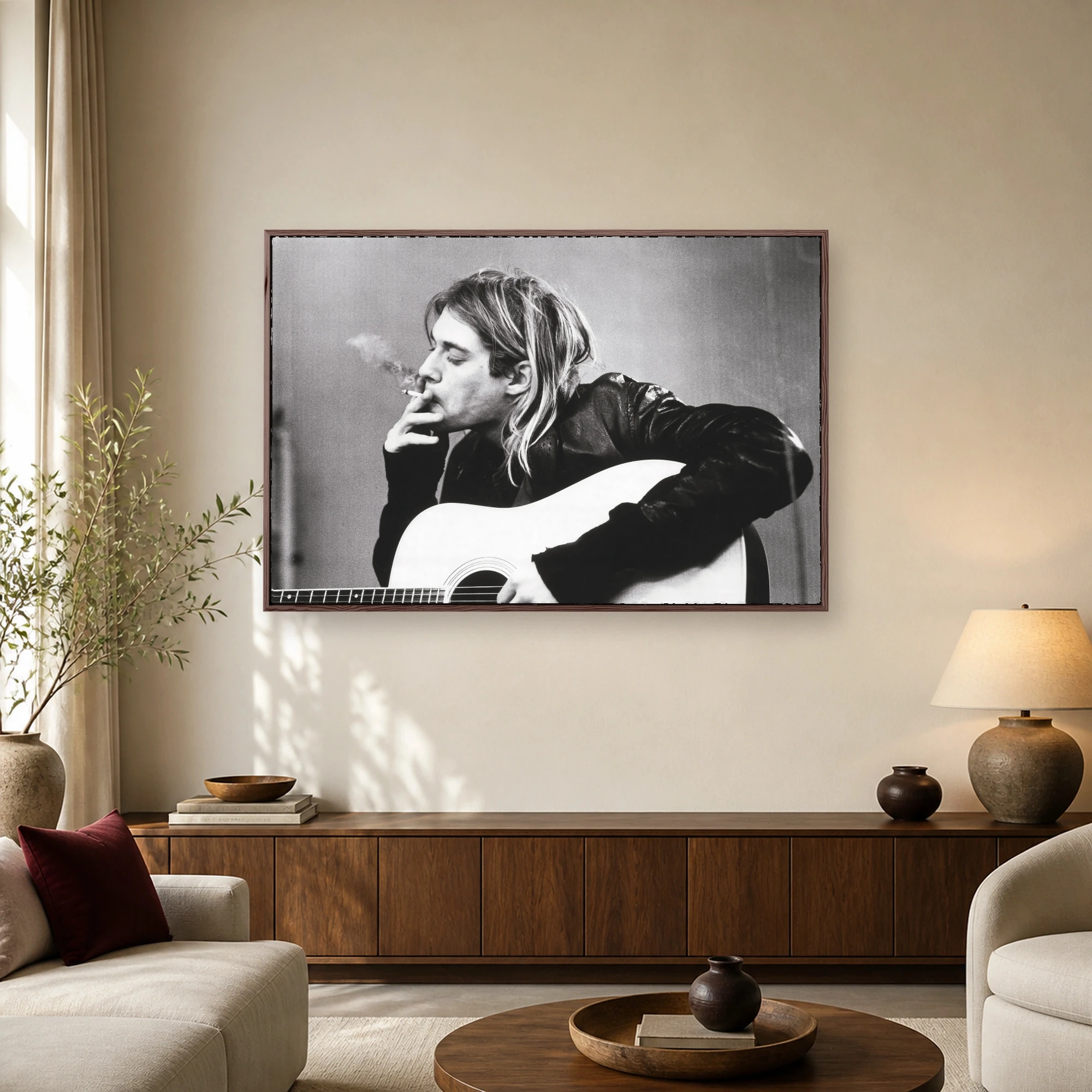 High contrast black and white photograph of Kurt Cobain playing an acoustic guitar while smoking a cigarette.