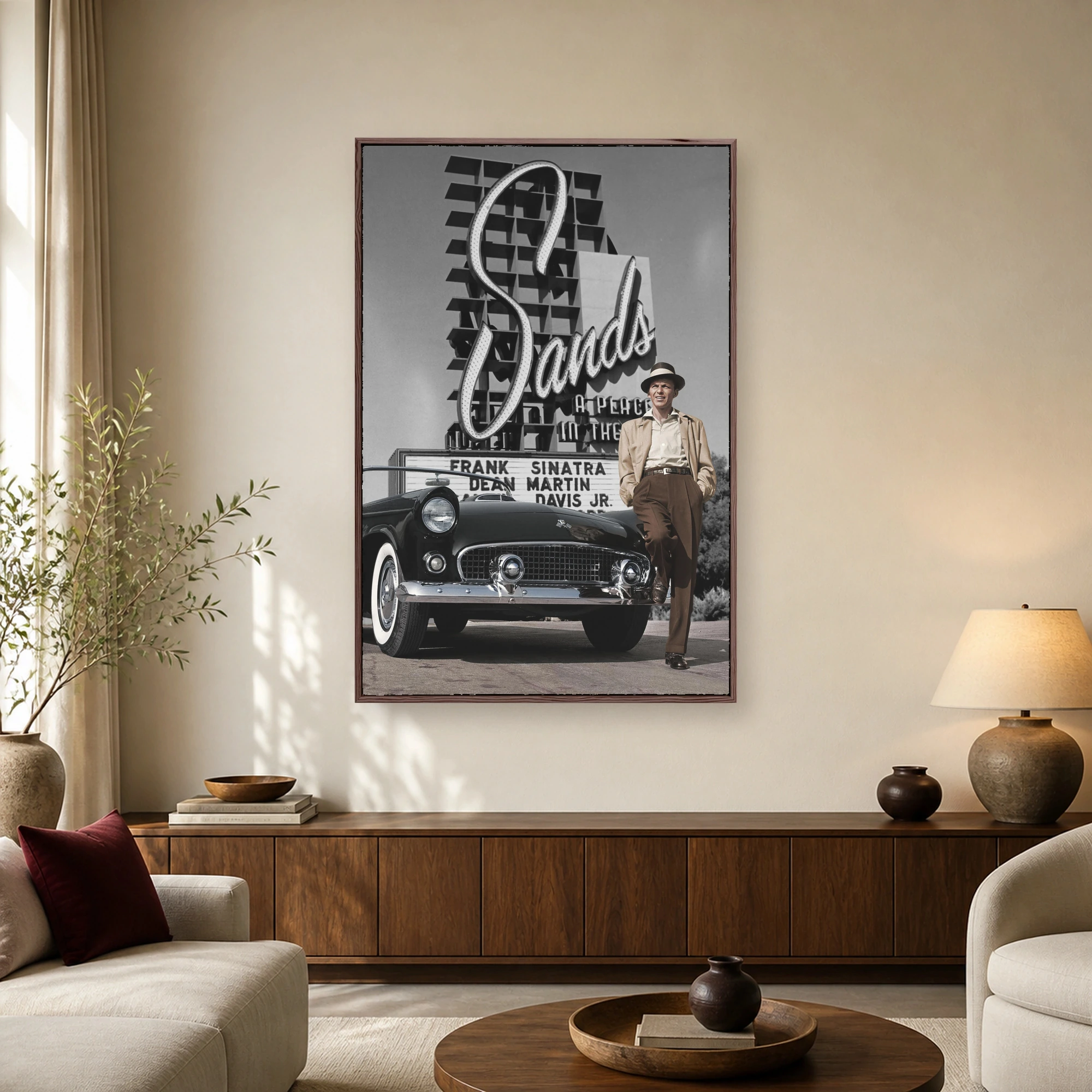 Frank Sinatra in a fedora hat leaning against a vintage black convertible car outside The Sands hotel marquee sign in Las Vegas.