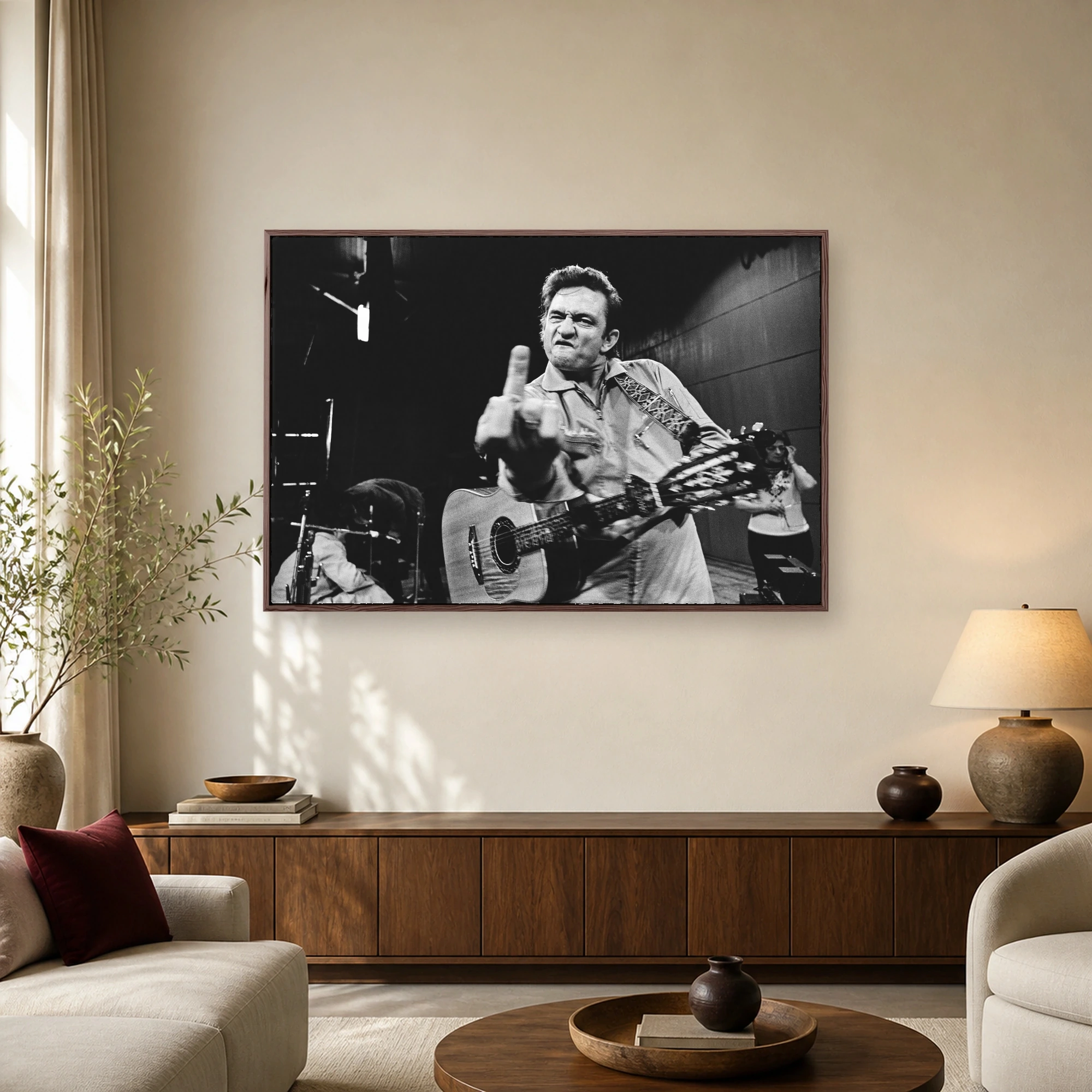 Black and white photograph of musician Johnny Cash gesturing with his middle finger while holding an acoustic guitar.