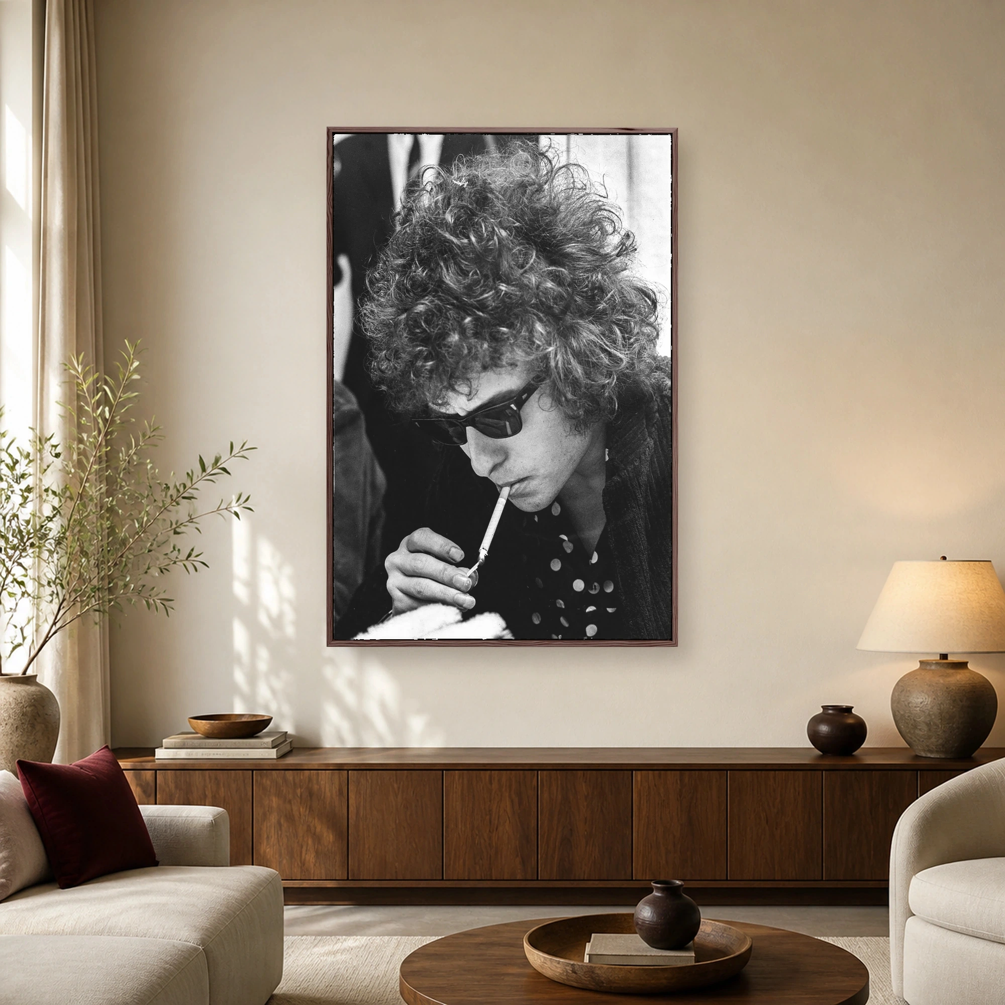 Black and white photo of Bob Dylan with curly hair, dark sunglasses, and a polka dot shirt lighting a cigarette.