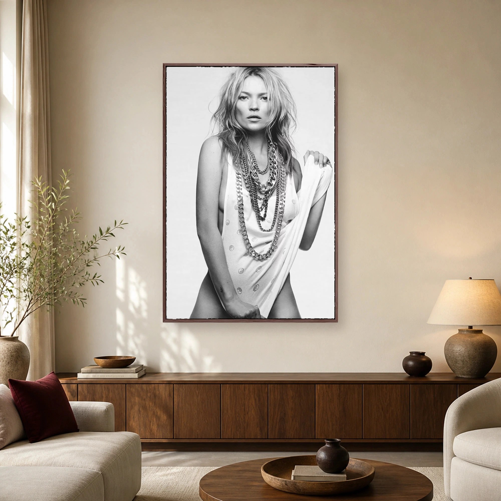 Black and white portrait of supermodel Kate Moss wearing layered heavy chain necklaces and a white tank top with tousled hair and a direct gaze.