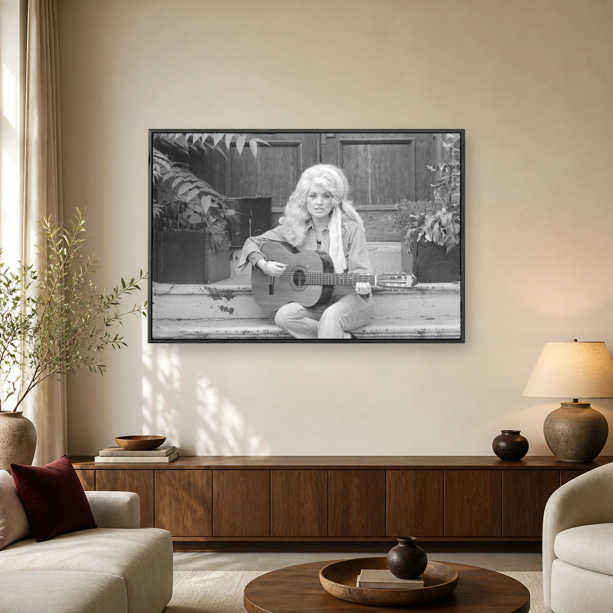 Vintage black and white photograph of Dolly Parton sitting on stone steps outdoors holding an acoustic guitar with potted plants and wooden doors in the background
