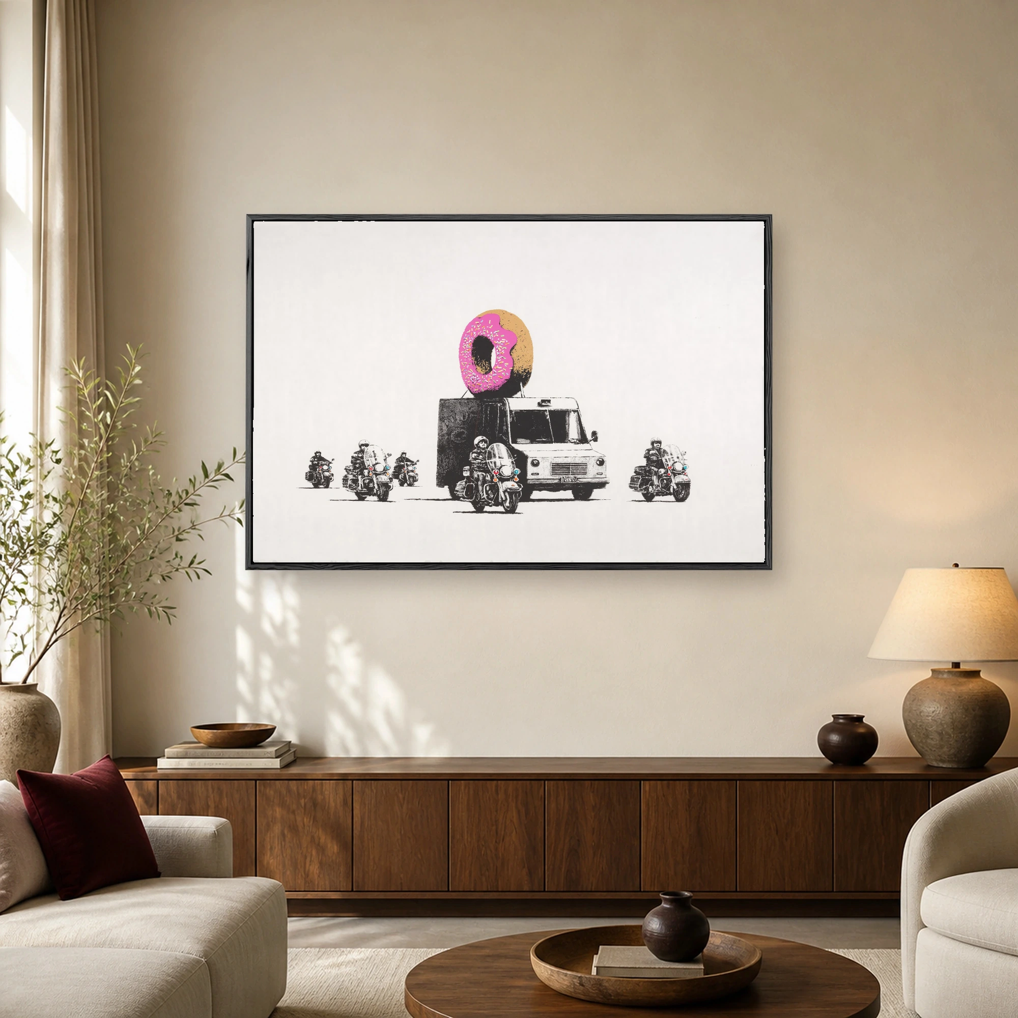 Black and white stencil artwork of police motorcycle officers escorting a truck topped with a large pink sprinkle donut on a cream background.