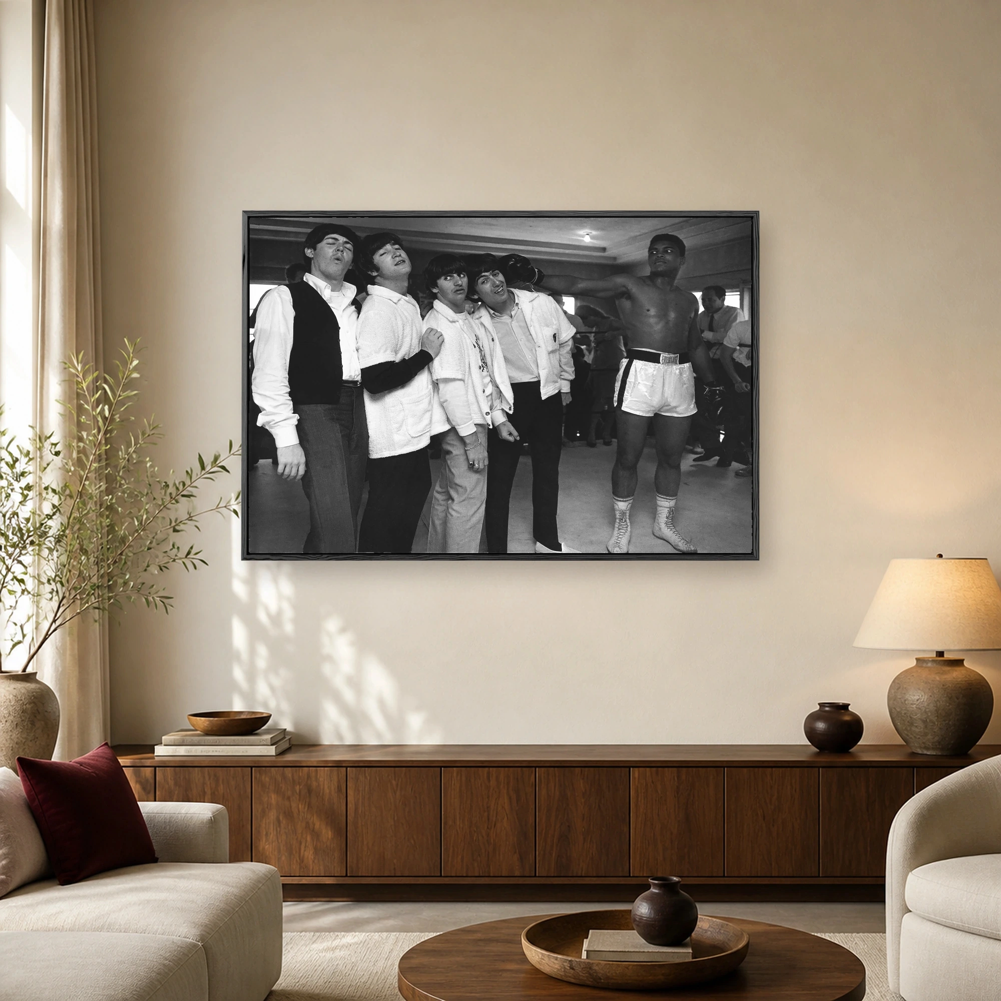 Historic black and white photograph of The Beatles reacting dramatically to a playful punch from boxer Muhammad Ali in a gym.